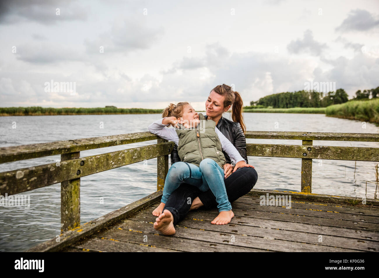Madre e figlia sul pontile di un lago Foto Stock