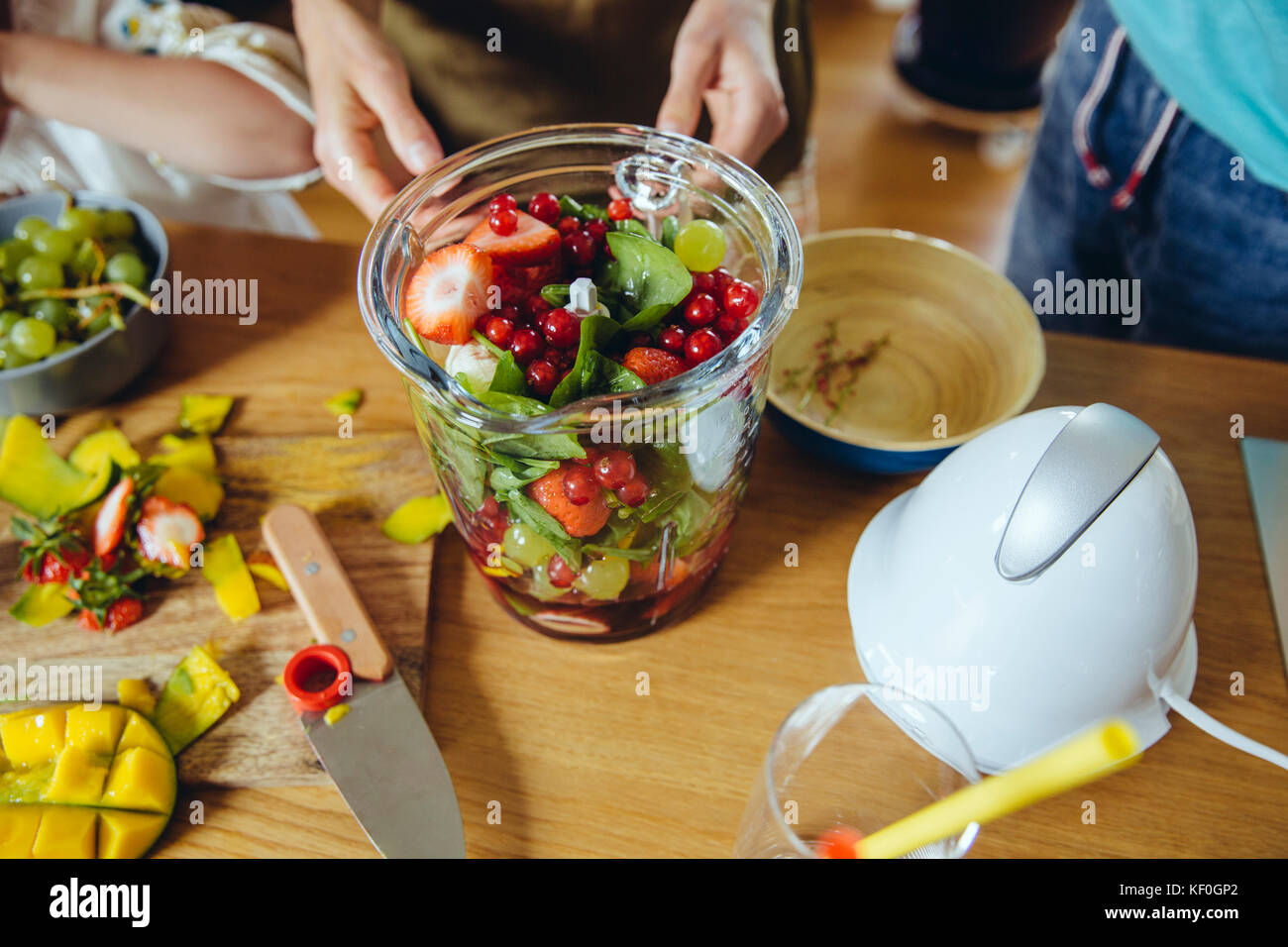 Close-up di madre e bambini mettendo la frutta in un frullatore smoothie Foto Stock