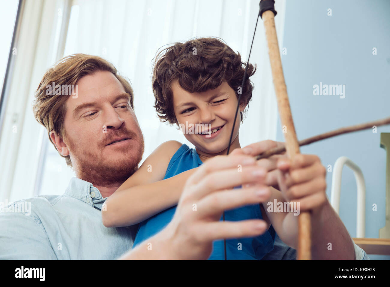 Padre figlio che mostra come utilizzare self-made arco e frecce Foto Stock