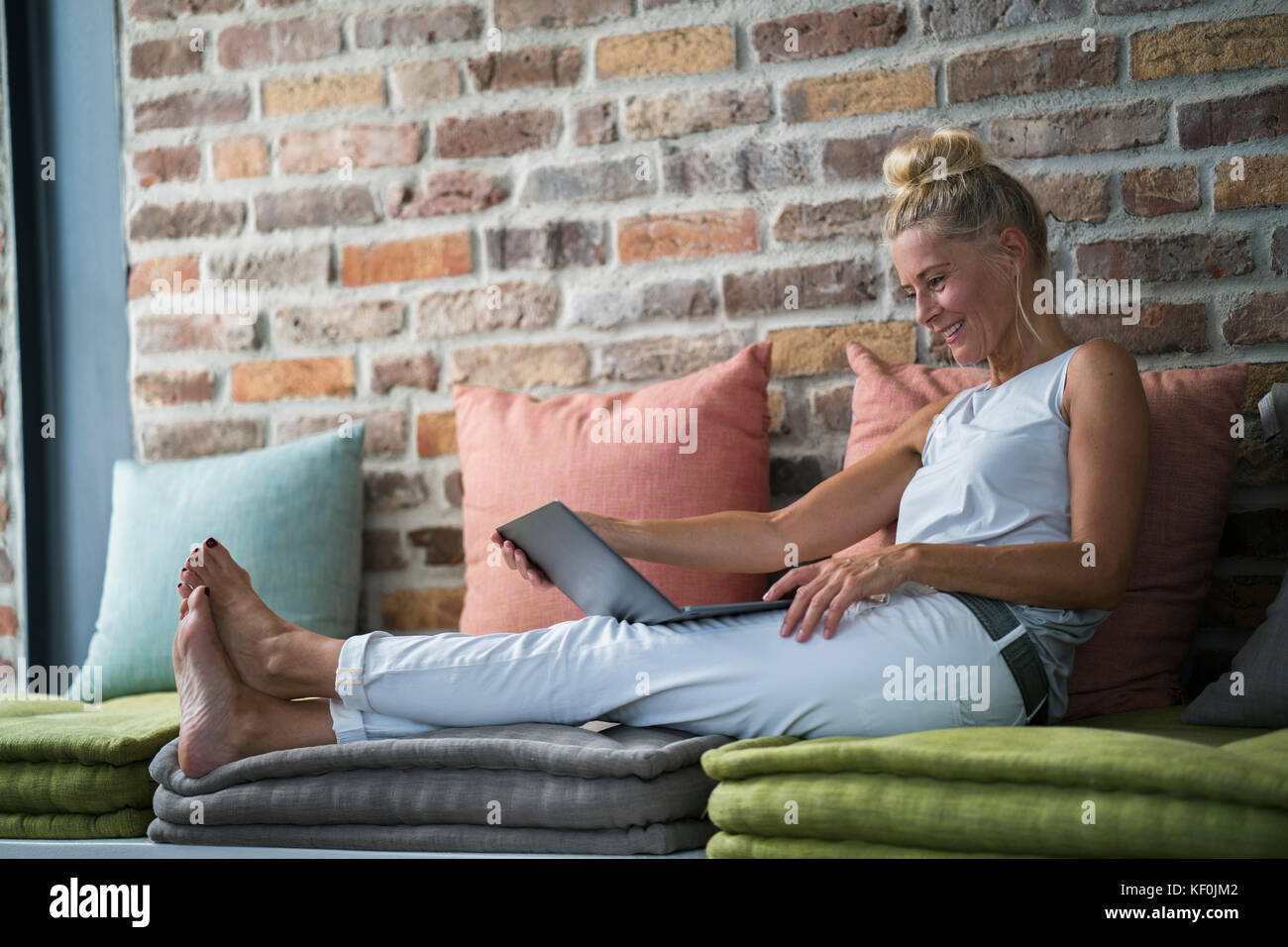 Donna matura seduta sul lettino, usine laptop Foto Stock