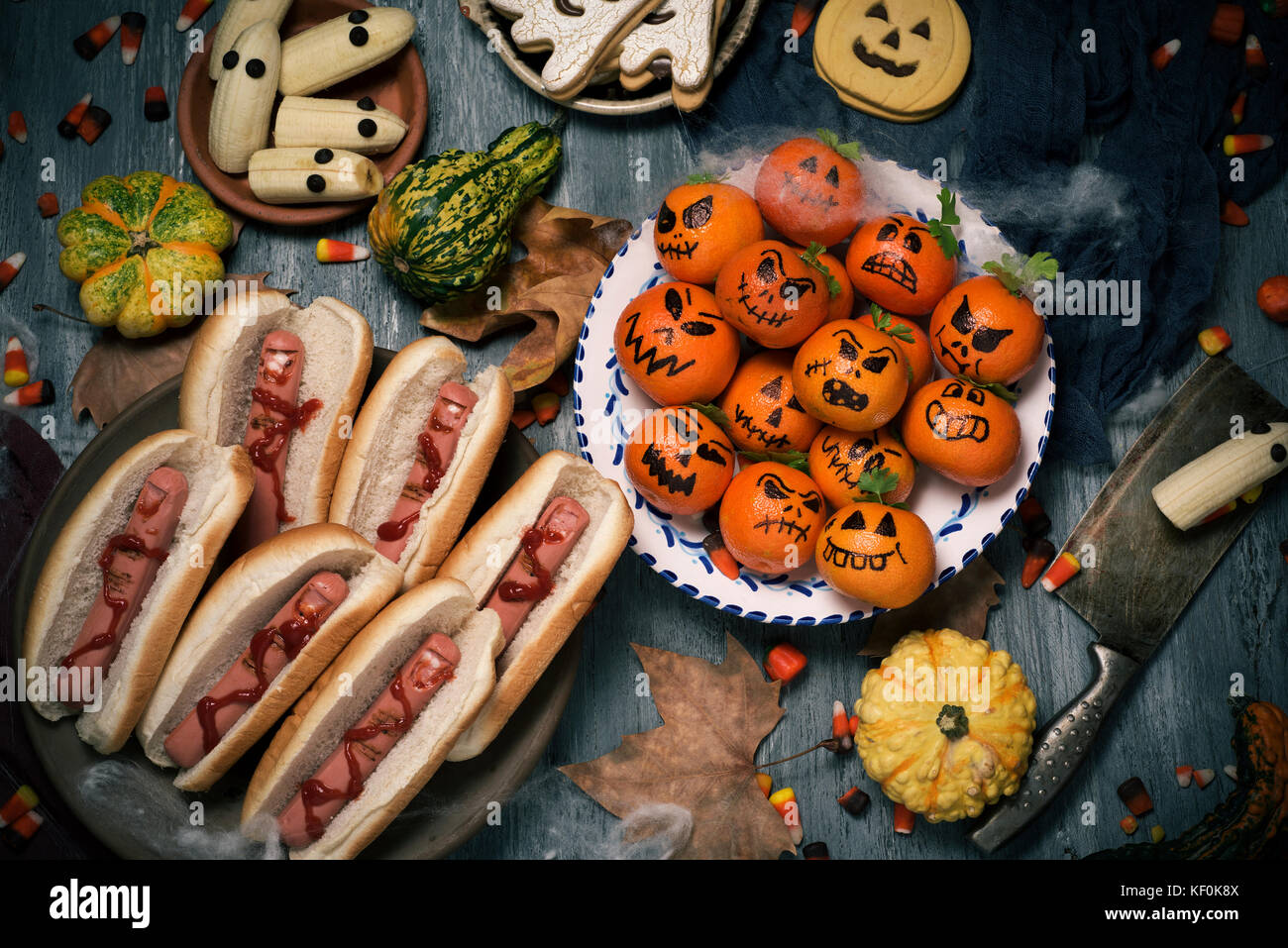 Alta angolazione di alcune divertenti halloween alimentari quali i tangerini come zucche intagliate con facce buffe, banane con gli occhi come fantasmi o hotdog nel sh Foto Stock