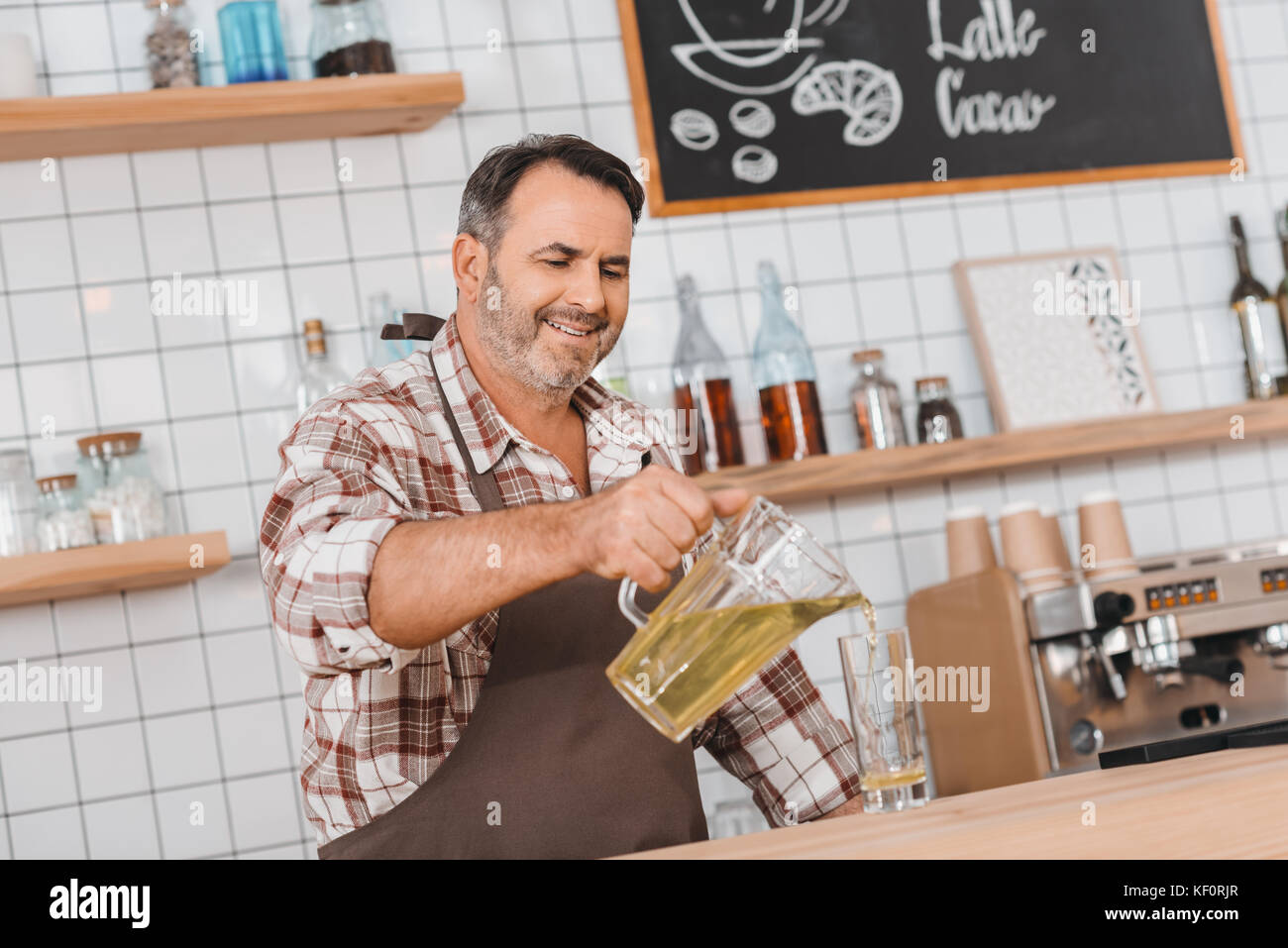 Barista versando il succo di mela in vetro Foto Stock