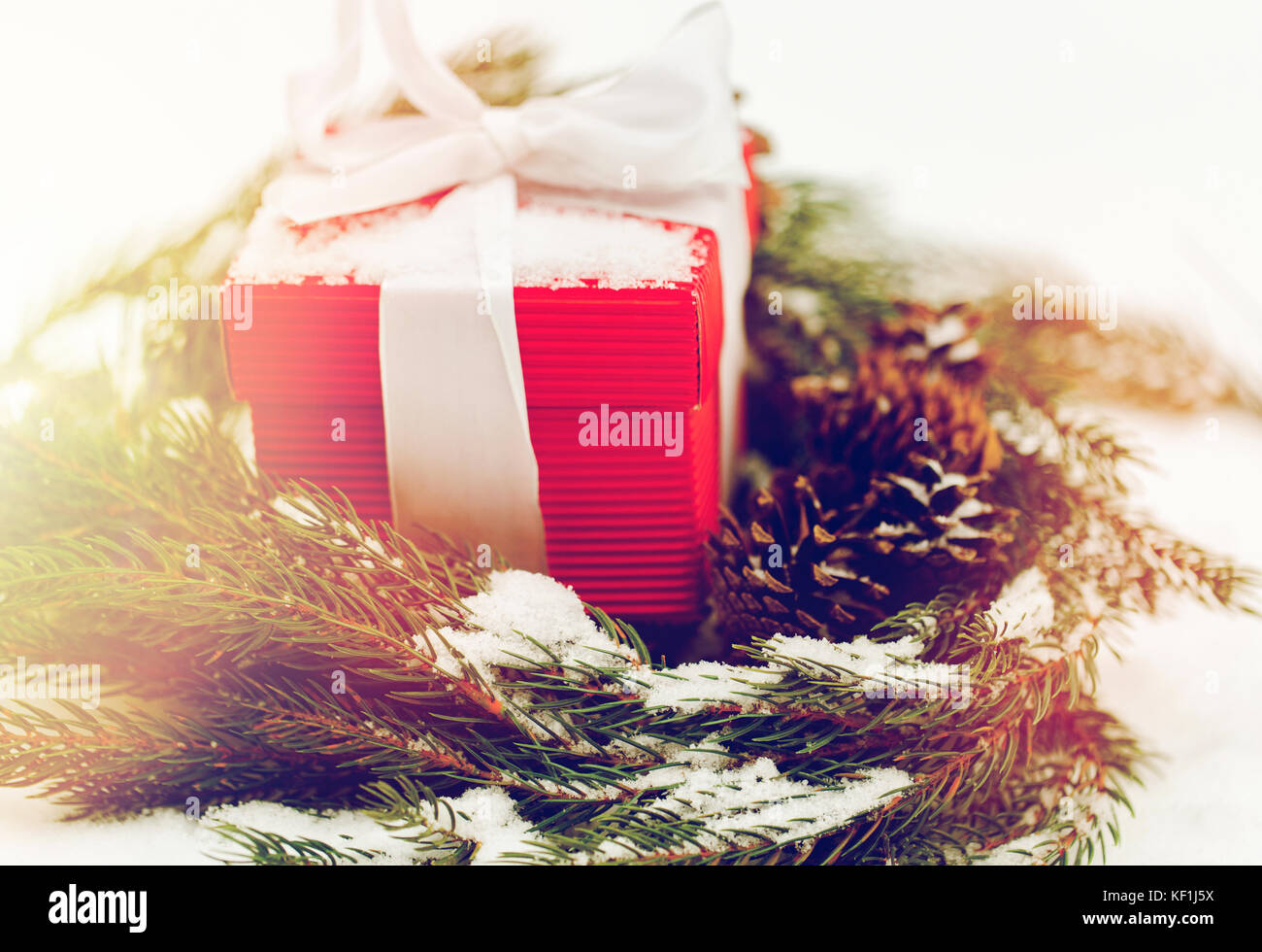 Regalo di natale e fir corona con i coni sulla neve Foto Stock