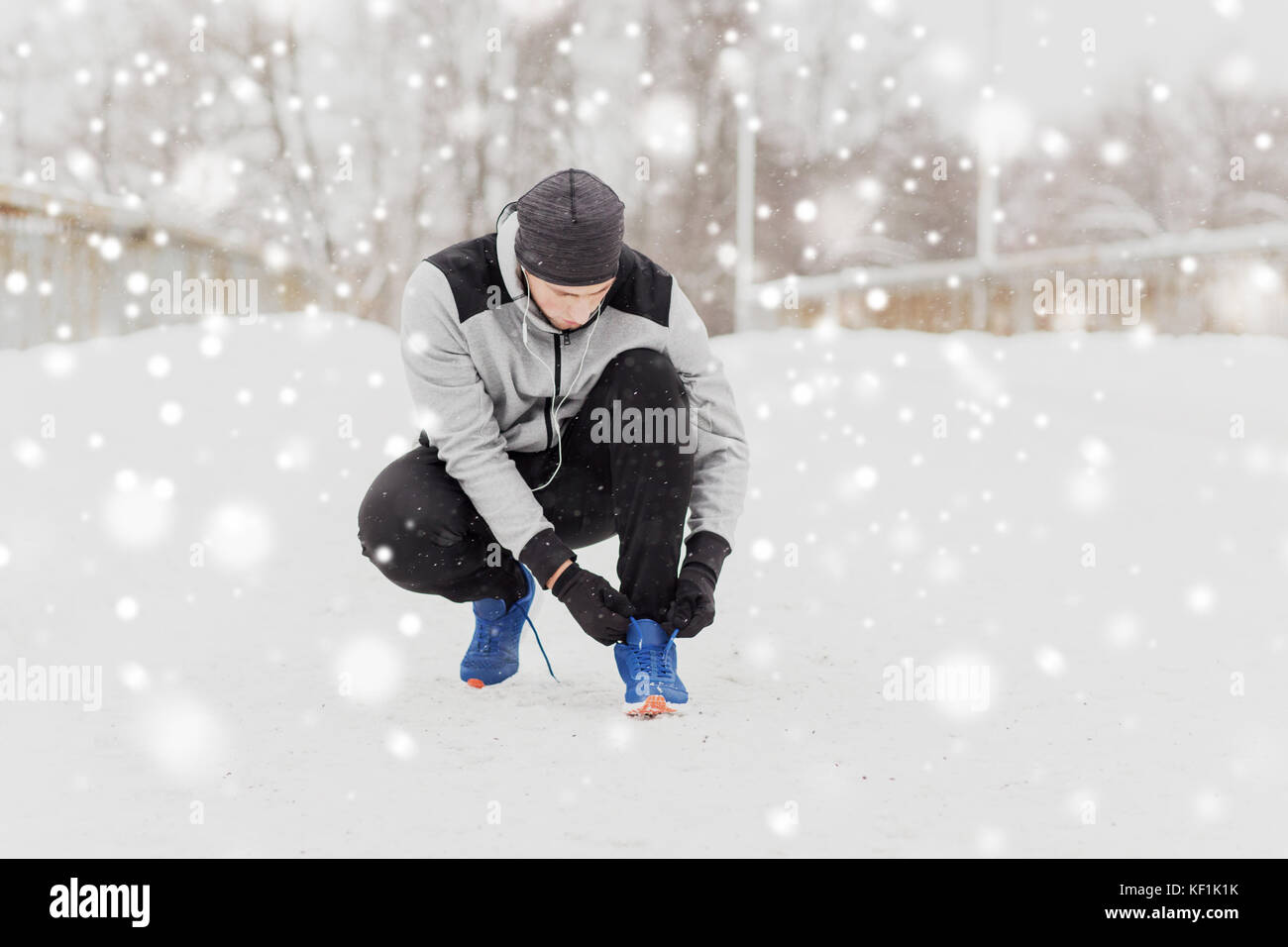 Uomo con gli auricolari la legatura calzatura sportiva in inverno Foto Stock