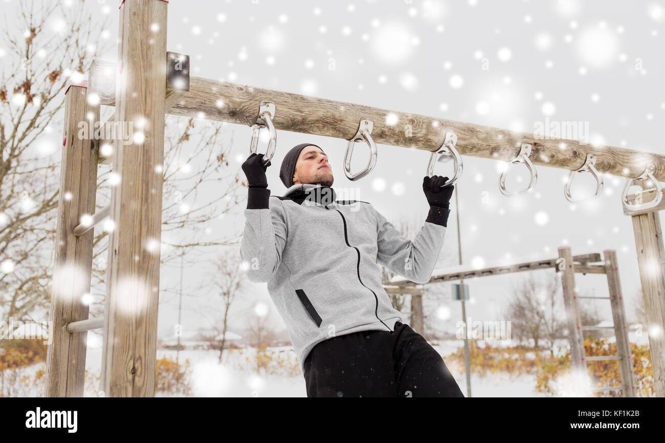 Giovane uomo che esercitano sulla barra orizzontale in inverno Foto Stock