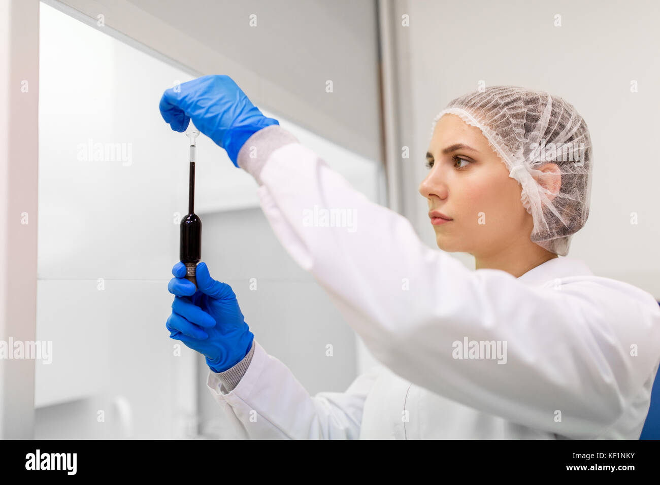 Donna con acido solforico in un contagocce in laboratorio Foto Stock