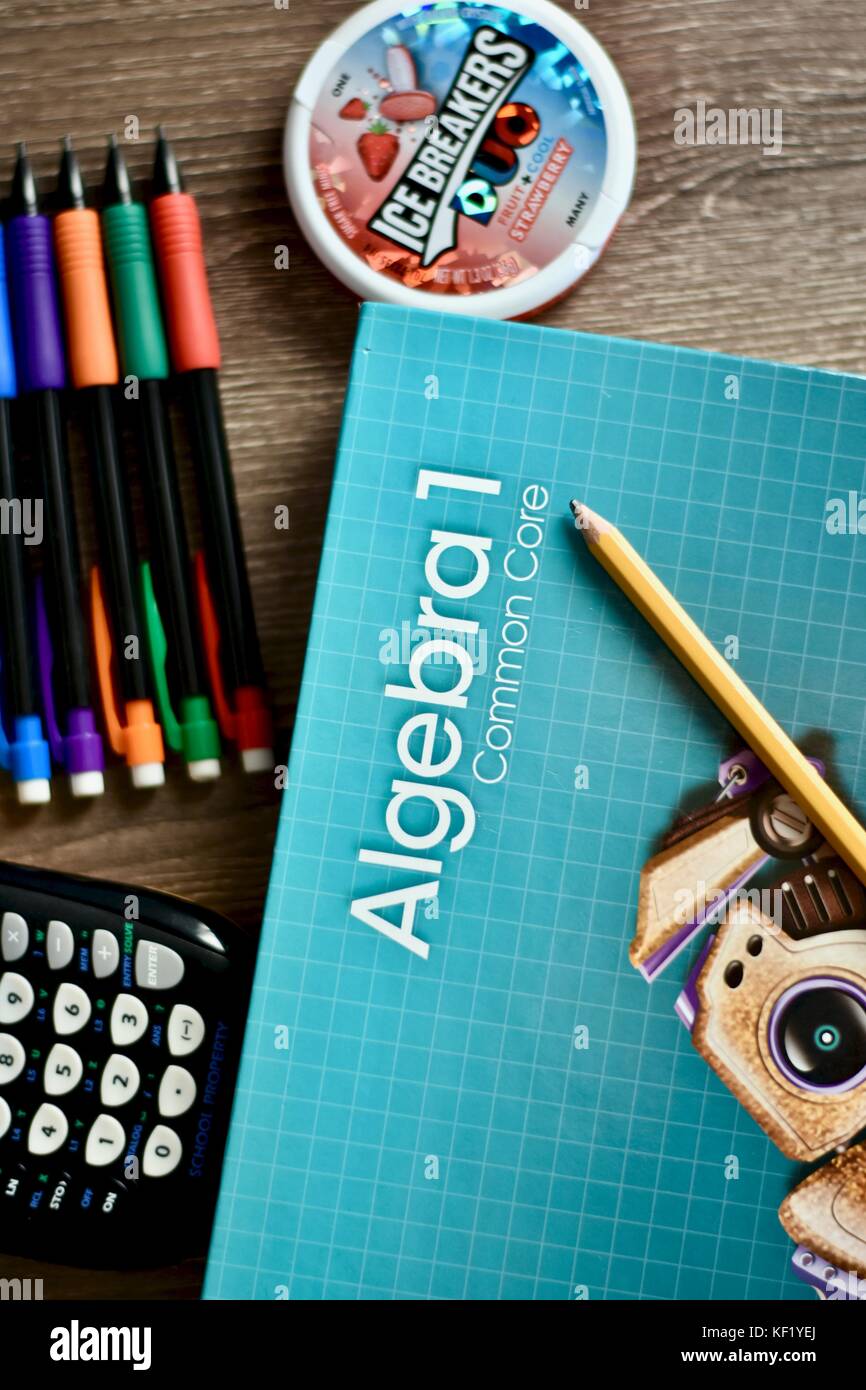 Libro di matematica sull'algebra sulla scrivania accanto ai materiali dell'aula Foto Stock
