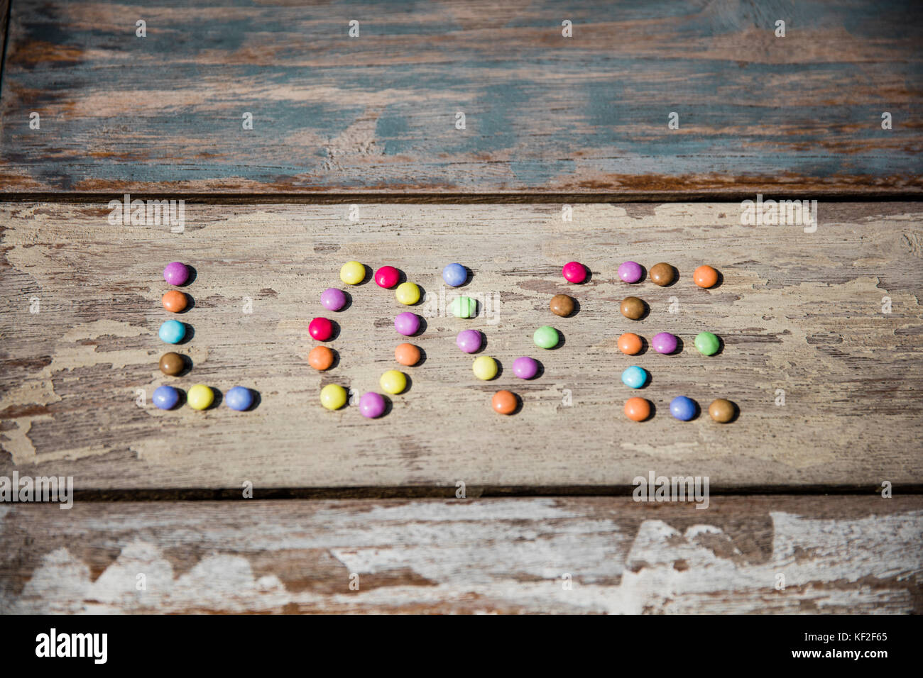 Gocce di cioccolato formando la parola amore sul tavolo di legno Foto Stock