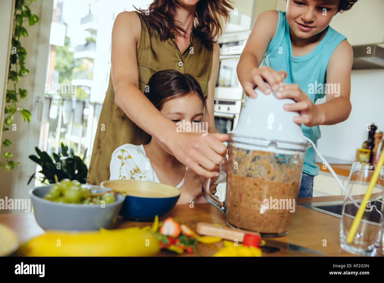 Madre e figli frutto di miscelazione per un smoothie Foto Stock