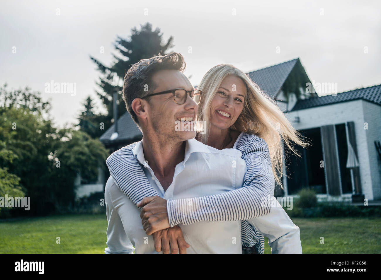 Coppia felice abbracciando nel giardino della loro casa di paese Foto Stock