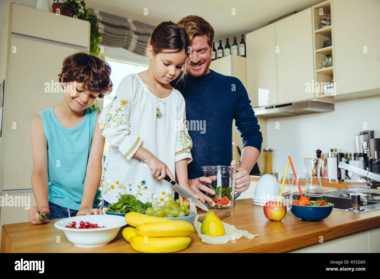 Padre e figli frutto di taglio per un smoothie Foto Stock