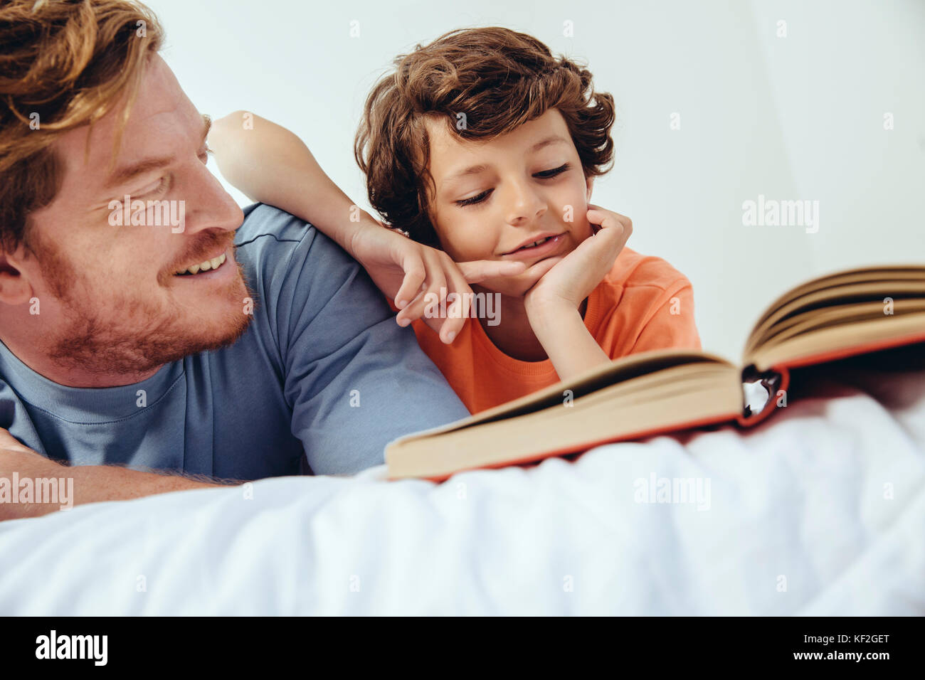 Padre e figlio libro di lettura a letto Foto Stock