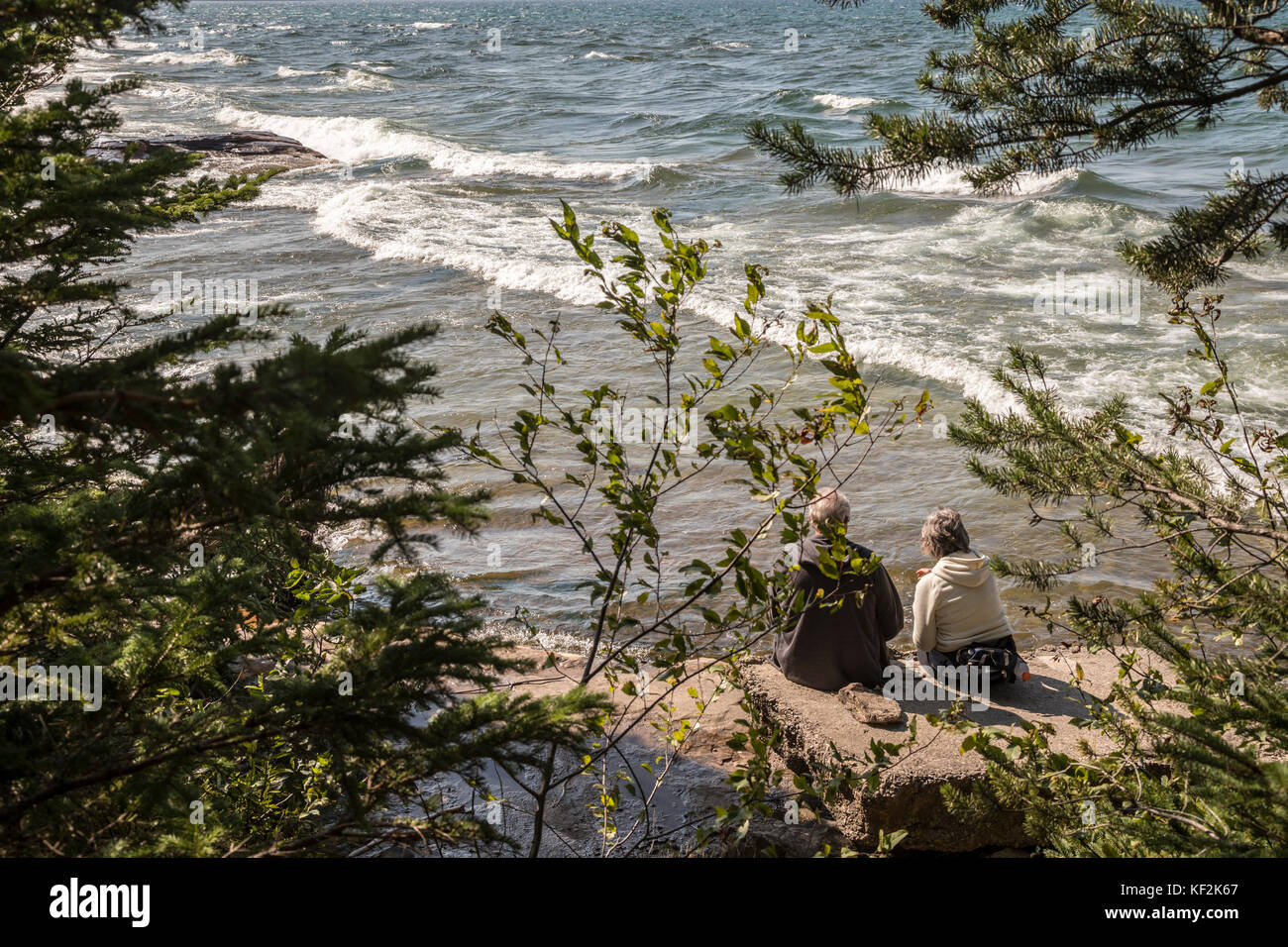 Munising, michigan - una coppia di anziani si siede su una roccia sulla riva del lago Superior in Pictured Rocks National Lakeshore. Foto Stock