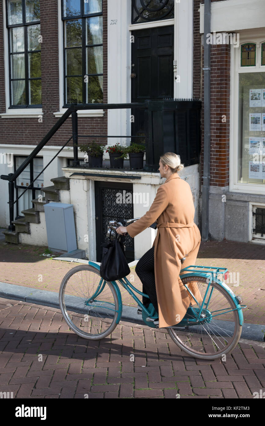 Donna in bicicletta la sua bici in amsterdam, Paesi Bassi Foto Stock