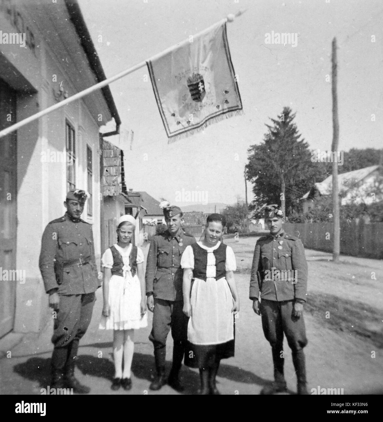Questa immagine raffigura un soldato che indossa un costume popolare, regge una bandiera e una medaglia, con uno stemma visibile, che simboleggia un evento storico o cerimoniale. L'uniforme rappresenta un abbigliamento militare tradizionale, che enfatizza il patrimonio culturale. Foto Stock