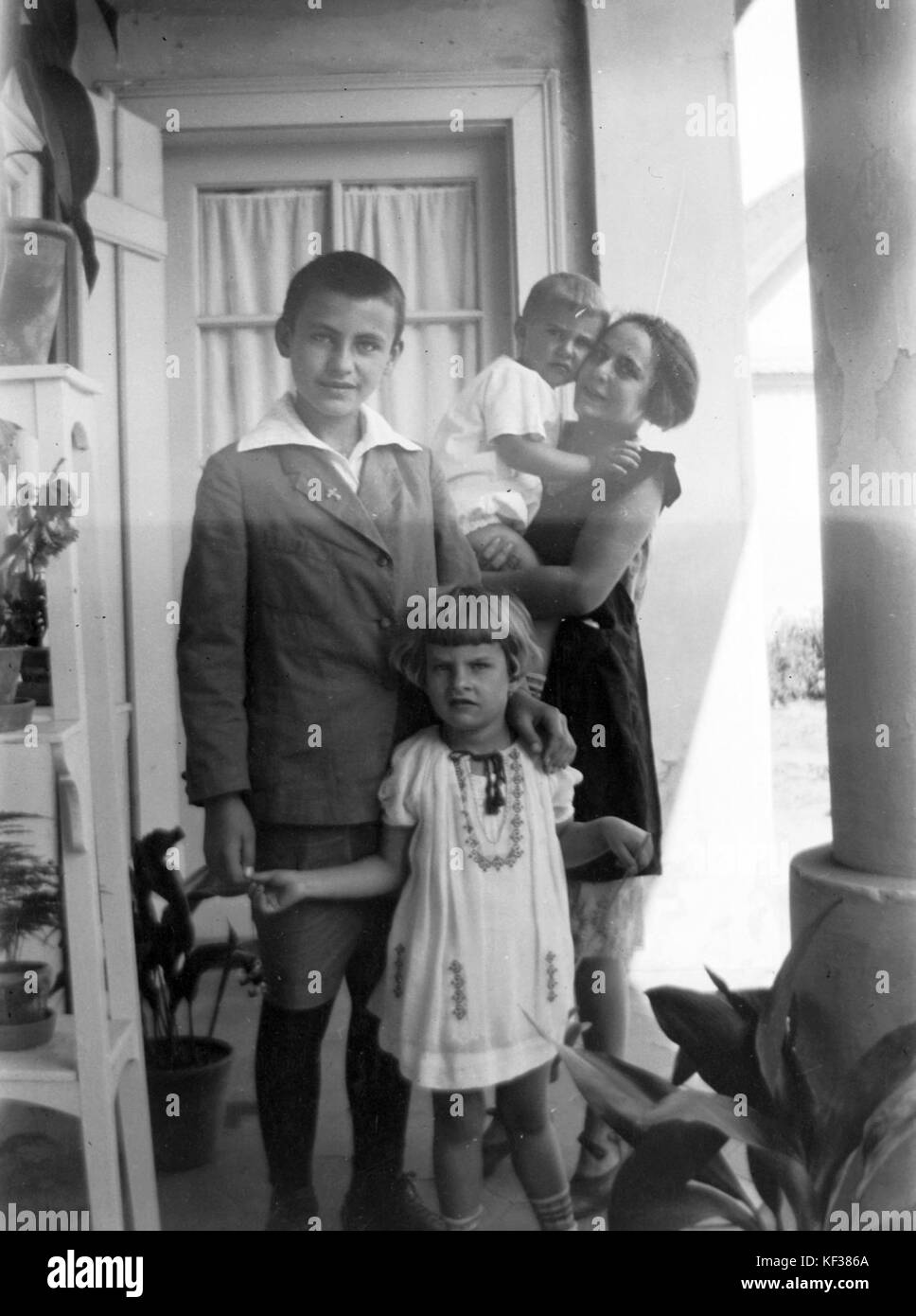 Una fotografia raffigurante bambini che si godono una giornata estiva su un portico, probabilmente durante l'inizio del XX secolo. L'immagine cattura la gioia e la semplicità dell'infanzia durante questa stagione. Foto Stock