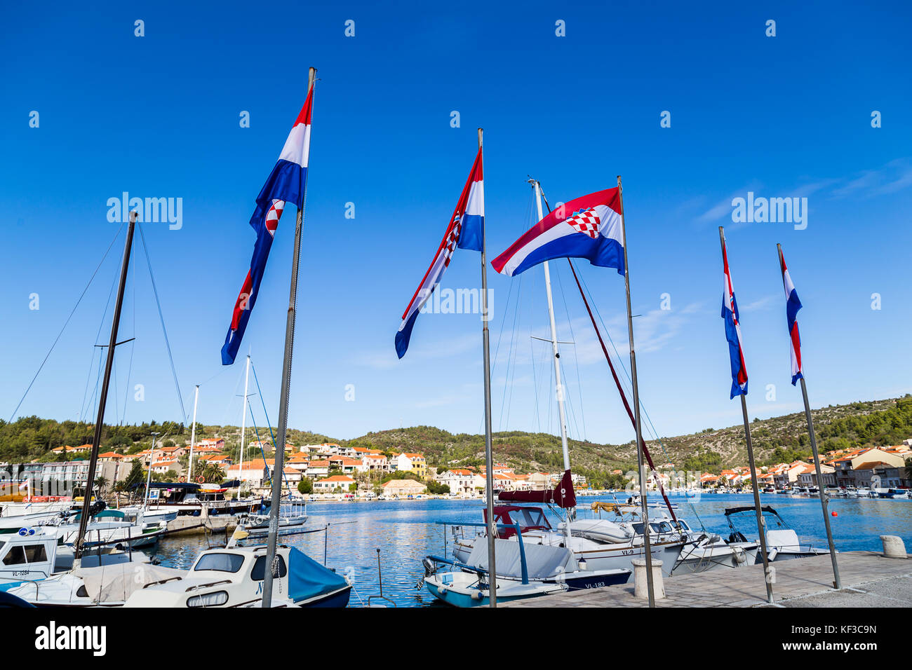 Un quintetto di colorati Bandiere croata visto sulla banchina di Vela luka, un piuttosto trafficata cittadina sull'estremo occidentale dell isola di Korcula. Foto Stock