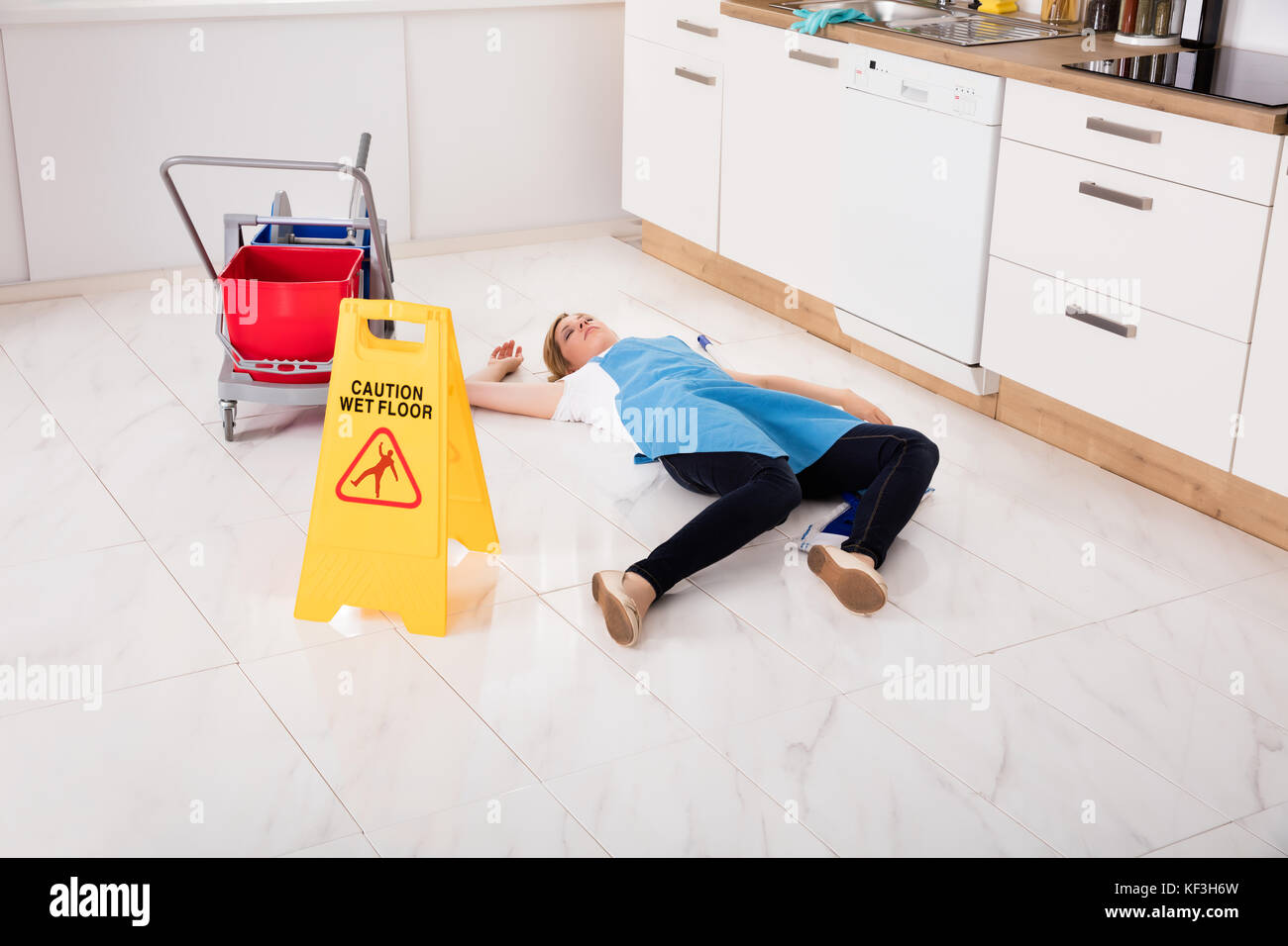 Giovane cameriera svenuti sdraiato sul pavimento in cucina. Incidente Concetto di compensazione Foto Stock