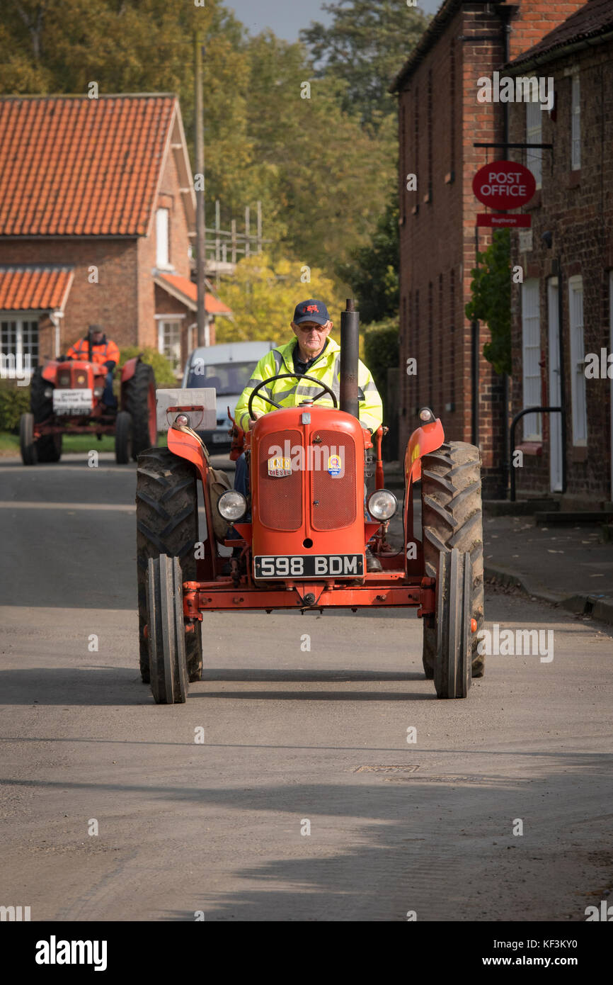 Uomo alla guida di red vintage BMC trattore attraverso il villaggio di Bugthorpe su Wolds Gruppo Vintage Road Run, annualmente un evento di beneficenza - Yorkshire, Inghilterra, Regno Unito. Foto Stock