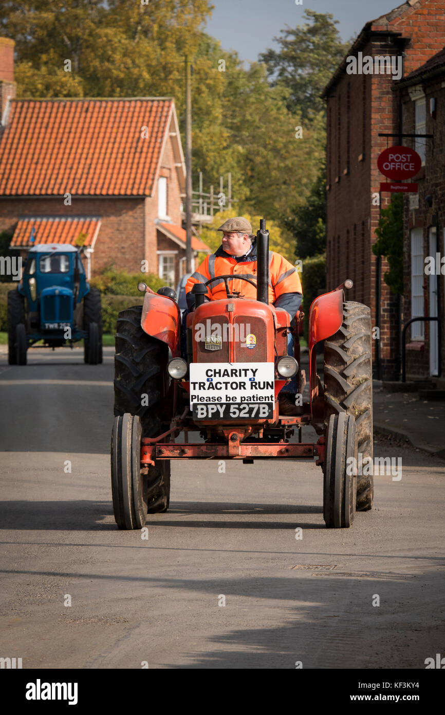 Uomo alla guida di red vintage BMC trattore attraverso il villaggio di Bugthorpe su Wolds Gruppo Vintage Road Run, annualmente un evento di beneficenza - Yorkshire, Inghilterra, Regno Unito. Foto Stock