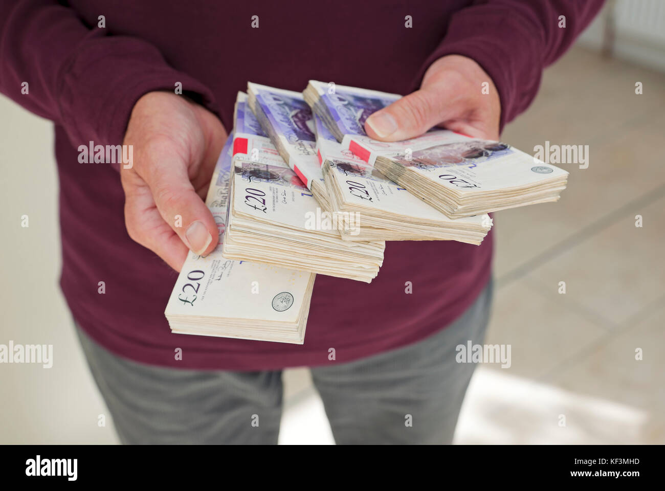 Primo piano della persona che detiene pacchetti di banconote inglesi da 20 sterline banconote in contanti pagamento di banconote riciclaggio di denaro attività criminali Inghilterra Regno Unito Foto Stock