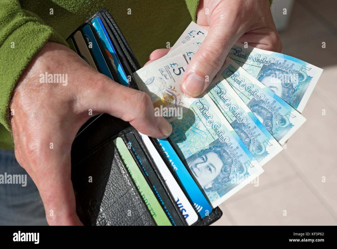 Primo piano di un uomo che prende banconote da 5 sterline banconote da 5 sterline banconote in moneta inglese da portafoglio in contanti Inghilterra Regno Unito Gran Bretagna Foto Stock