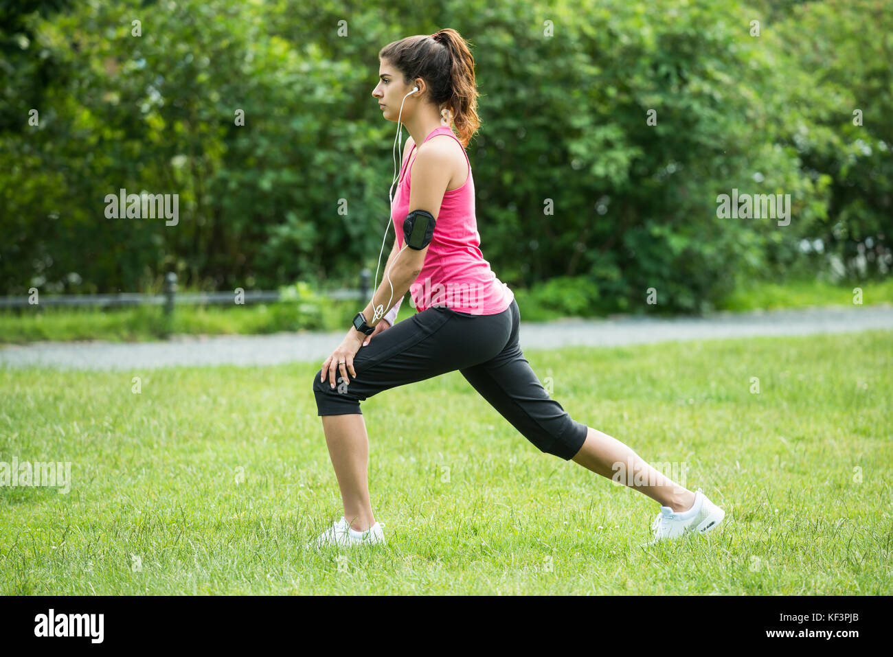 Giovane donna Stretching le gambe mentre ti alleni in posizione di parcheggio Foto Stock