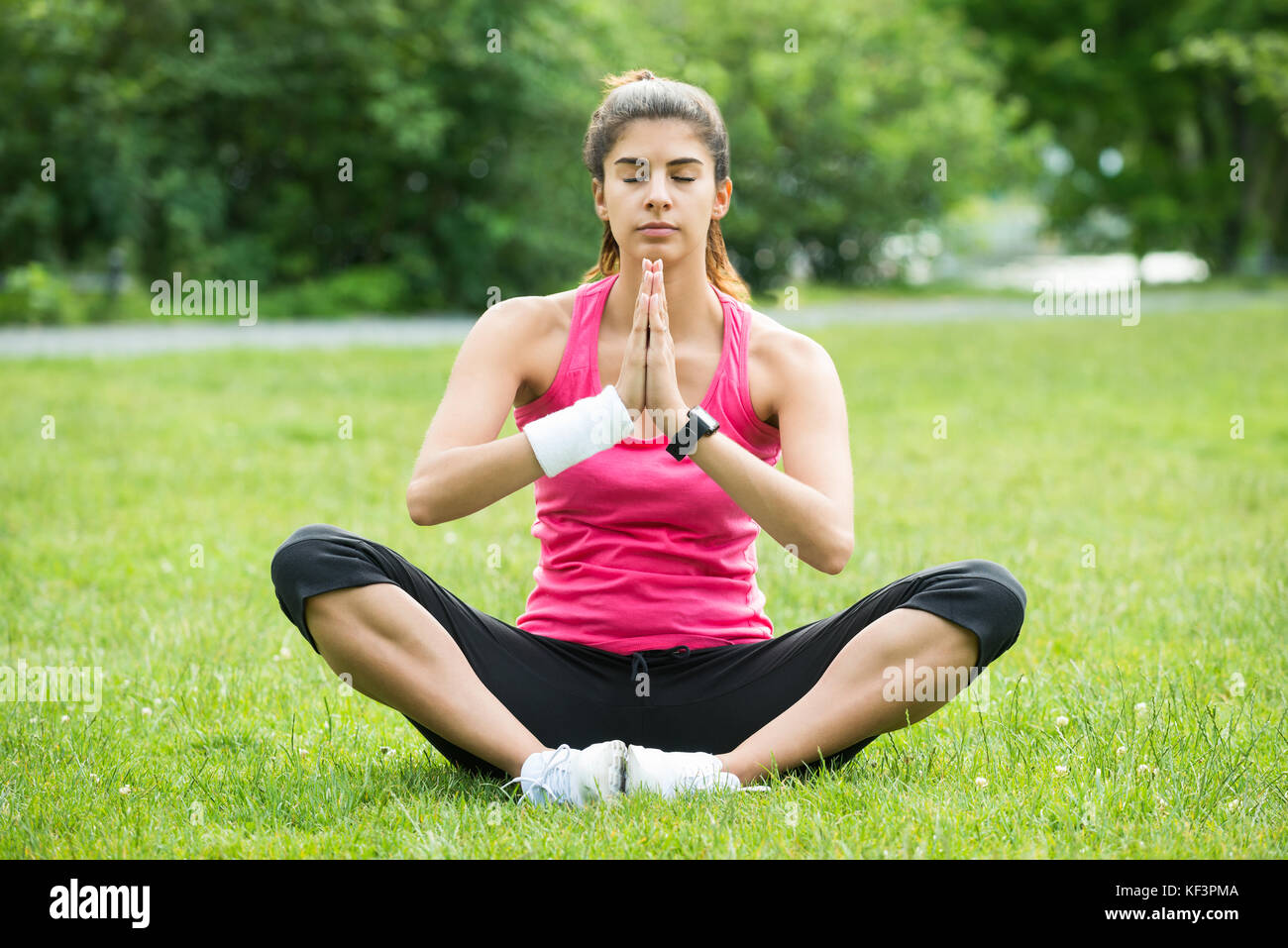 Giovane donna seduta su erba facendo meditazione in posizione di parcheggio Foto Stock