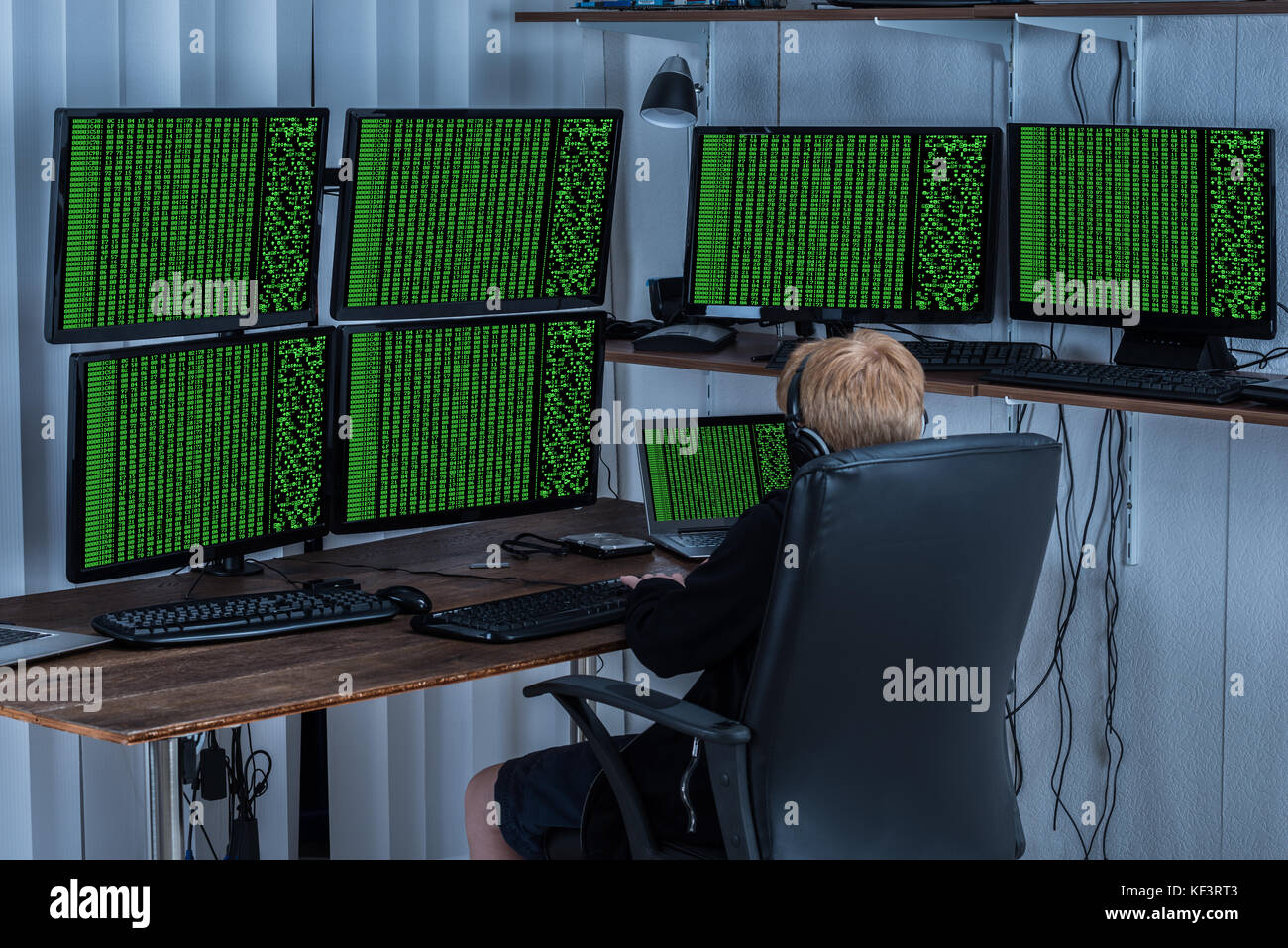 Bambino utilizzando più computer con codice binario sullo schermo Foto Stock