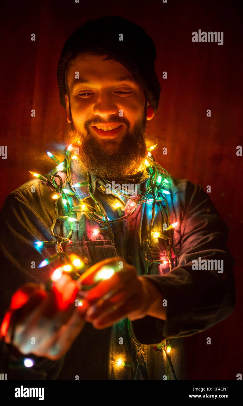 Uomo Barbuto avvolto in colorate luci di Natale Foto Stock