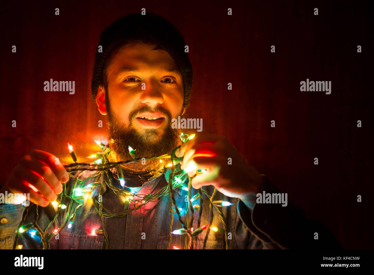 Uomo Barbuto avvolto in colorate luci di Natale Foto Stock