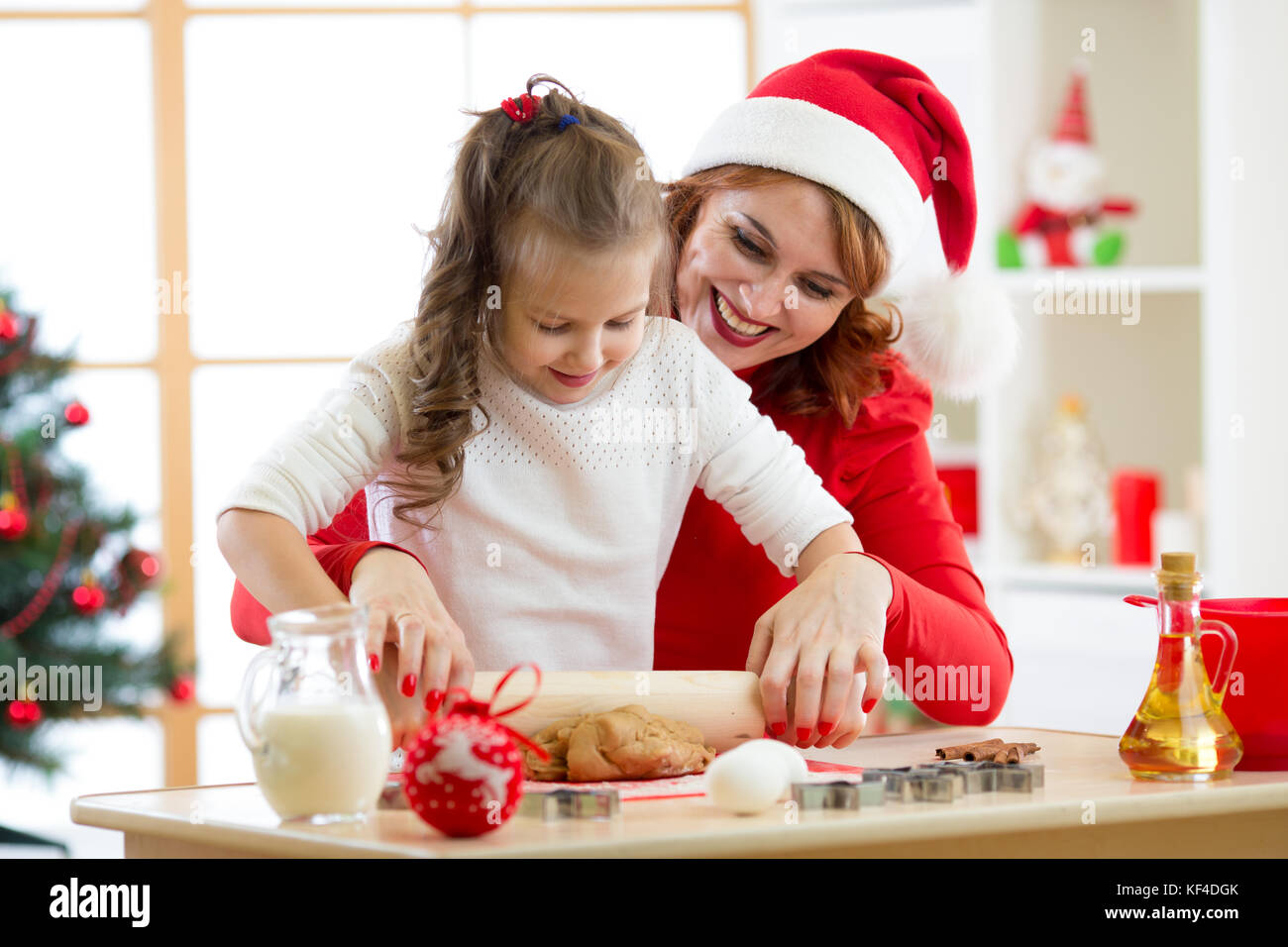 Felice donna e bambino ragazza stirando il natale pasta biscotto insieme Foto Stock