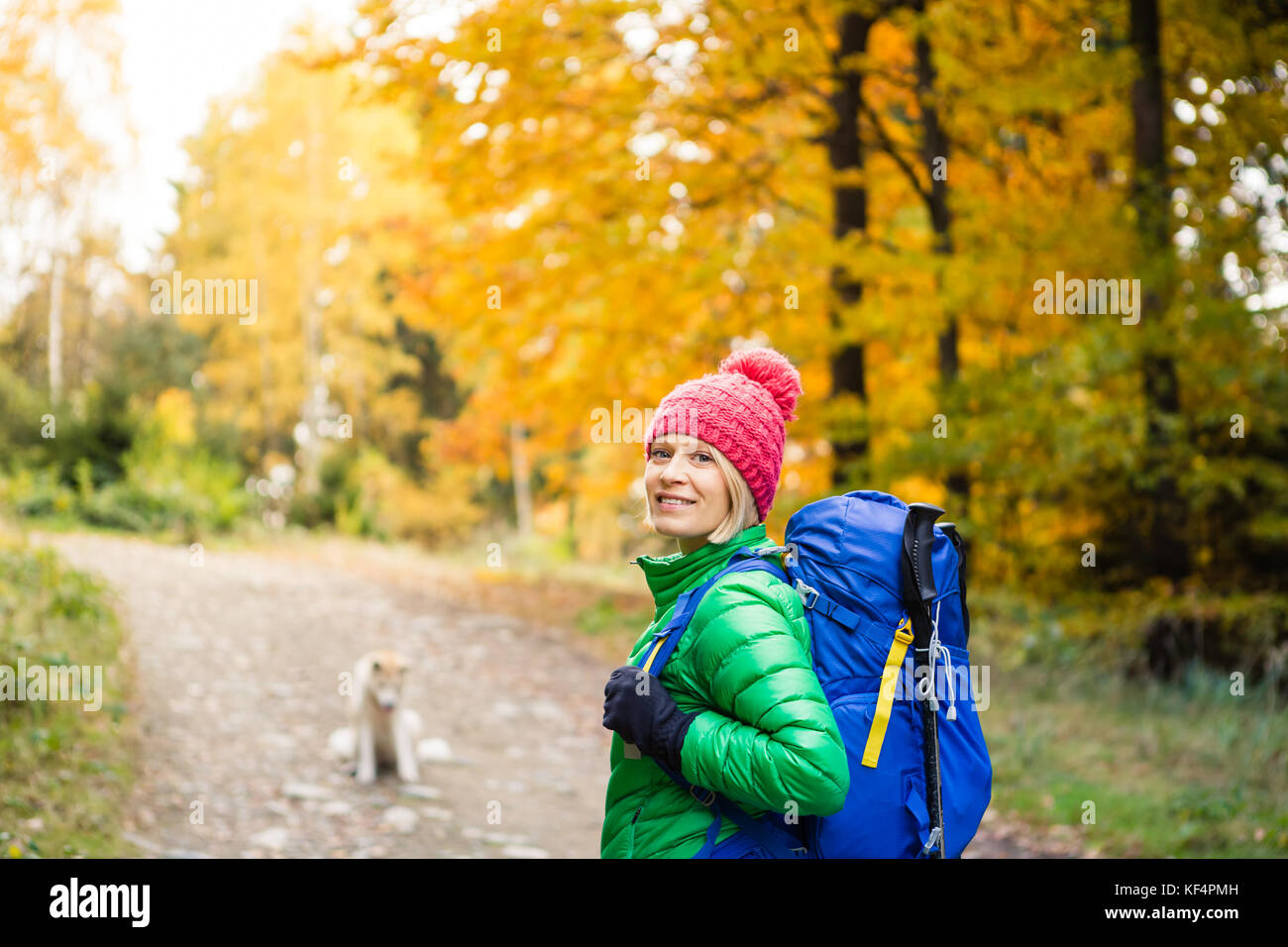 Escursionismo donna con zaino guardando la fotocamera e di ispirazione autunno golden boschi. Viaggi fitness e uno stile di vita sano all'aperto nella stagione autunnale. Trav Foto Stock
