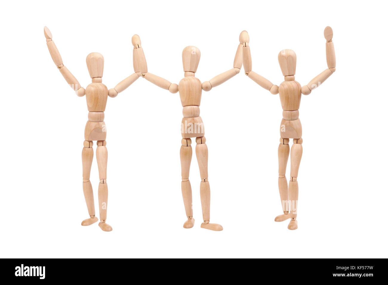 Tre manichini in legno che tiene insieme le mani in alto come vincitori isolati su sfondo bianco Foto Stock
