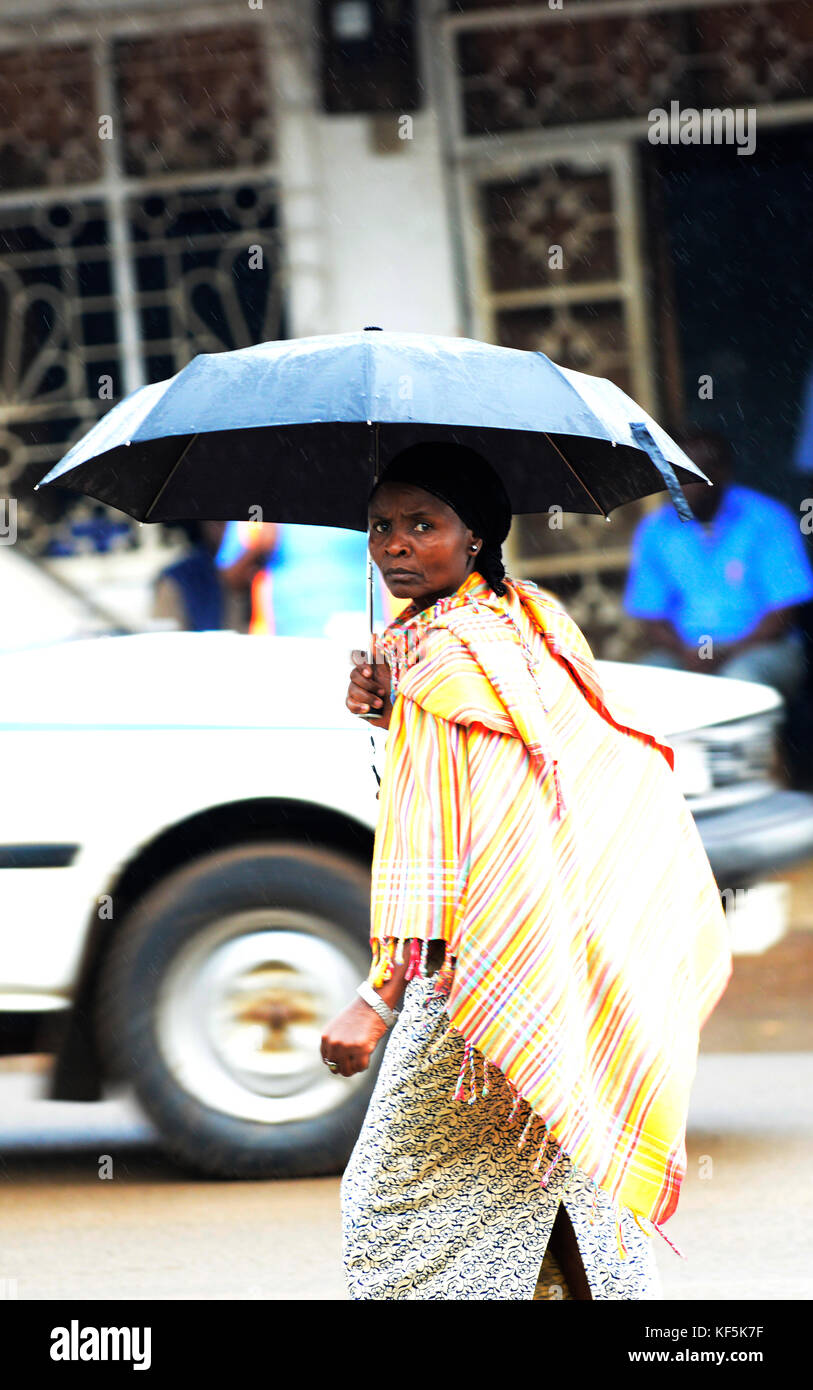 Una donna della Tanzania a piedi sotto la pioggia. Foto Stock