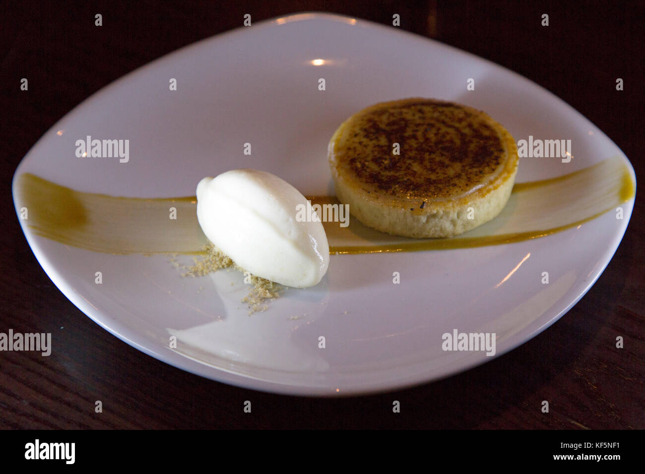 Un dessert di crostata di caramello salato servito con gelato. Il piatto su cui viene servito presenta una striscia di caramello. Foto Stock