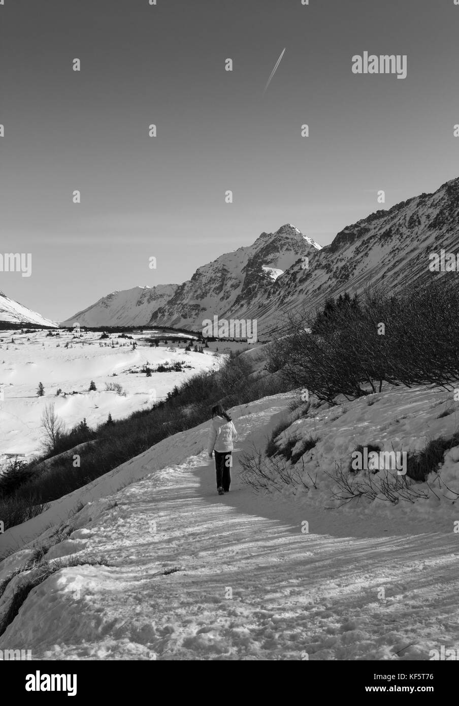 Nella grande terra. immagine in bianco e nero di lone persona in abbigliamento invernale a piedi lungo il sentiero innevato. mountain range in background. Foto Stock