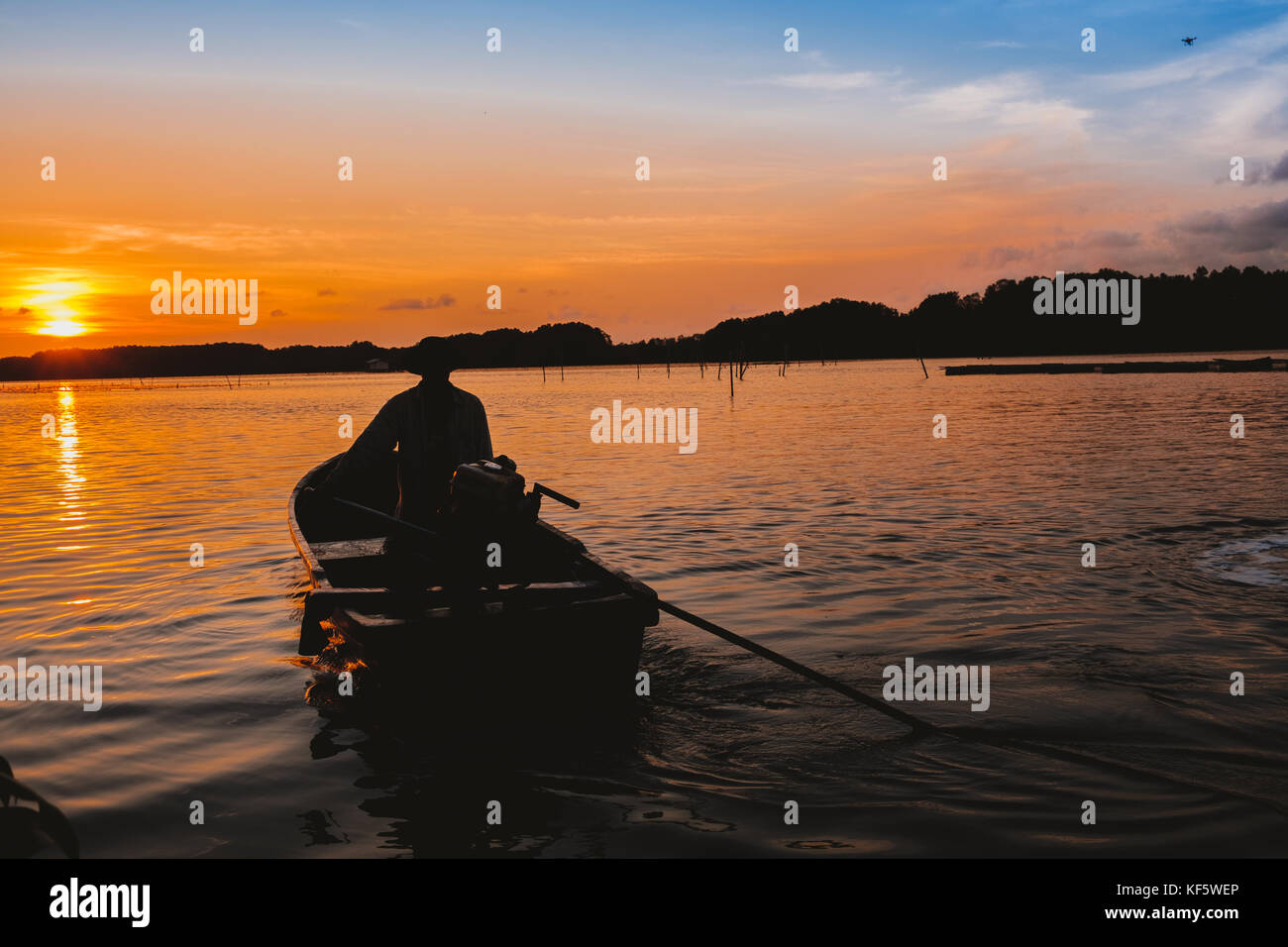 Tramonto di sera un uomo in sella alla sua barca dalla coda lunga in Thailandia. Foto Stock