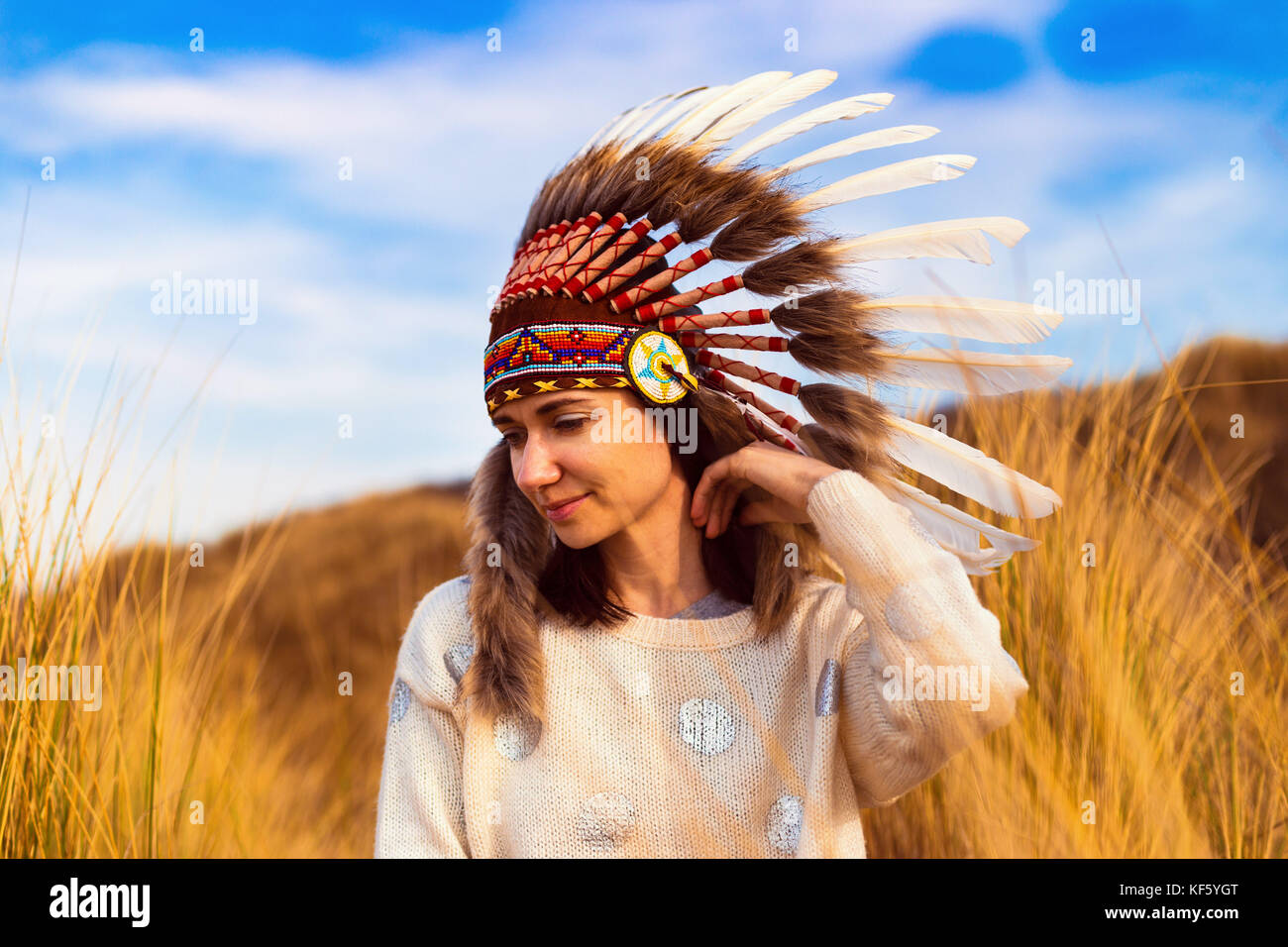 Bella giovane donna in nero punteggiato bianco capo stile nativo americano headdress durante il tramonto Foto Stock