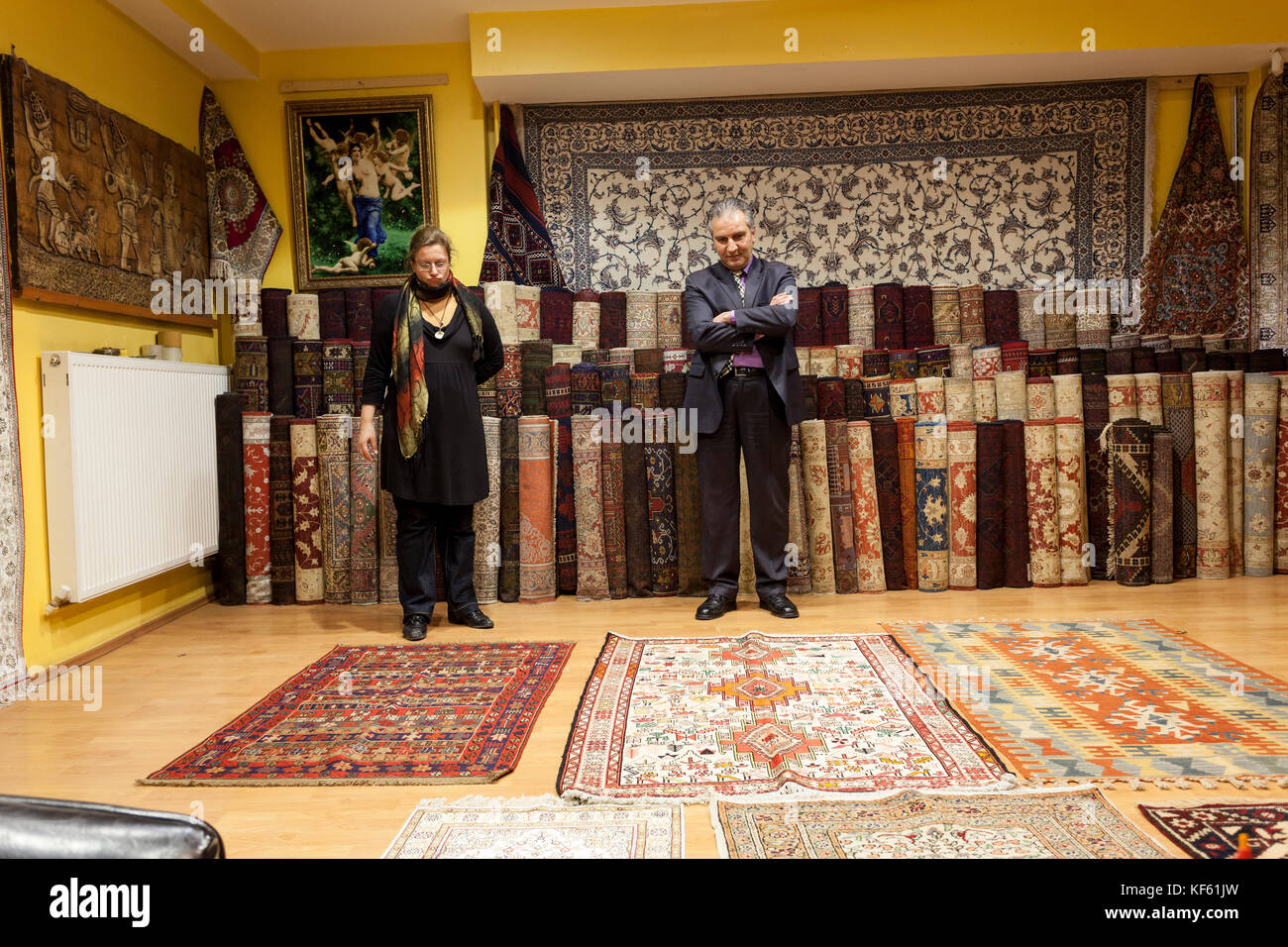 Venditore di tappeti offrendo colorati tappeti orientali al suo negozio Foto Stock