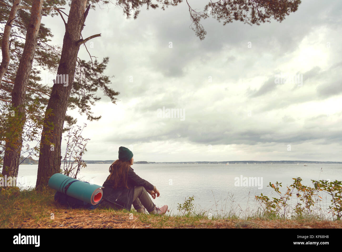 In viaggio lonely donna seduta vicino al lago di foresta e guardando lontano Foto Stock