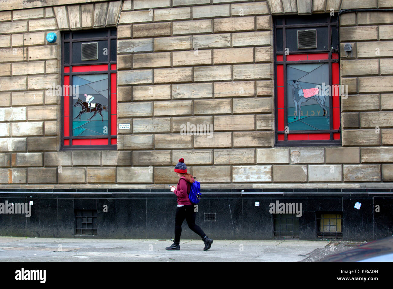 Gioco d'azzardo, corse di cavalli, negozio di scommesse greyhound Dog con immagini di giovani che camminano lungo Glasgow Street Foto Stock