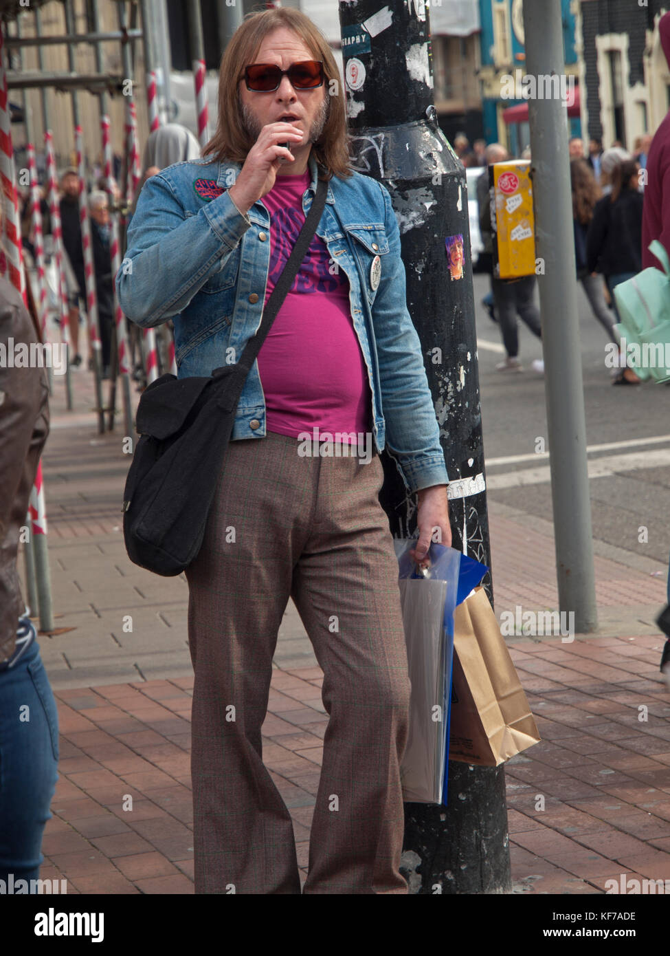 Un amante di 70s la moda si appoggia contro una lampada posta nel centro di Brighton Foto Stock