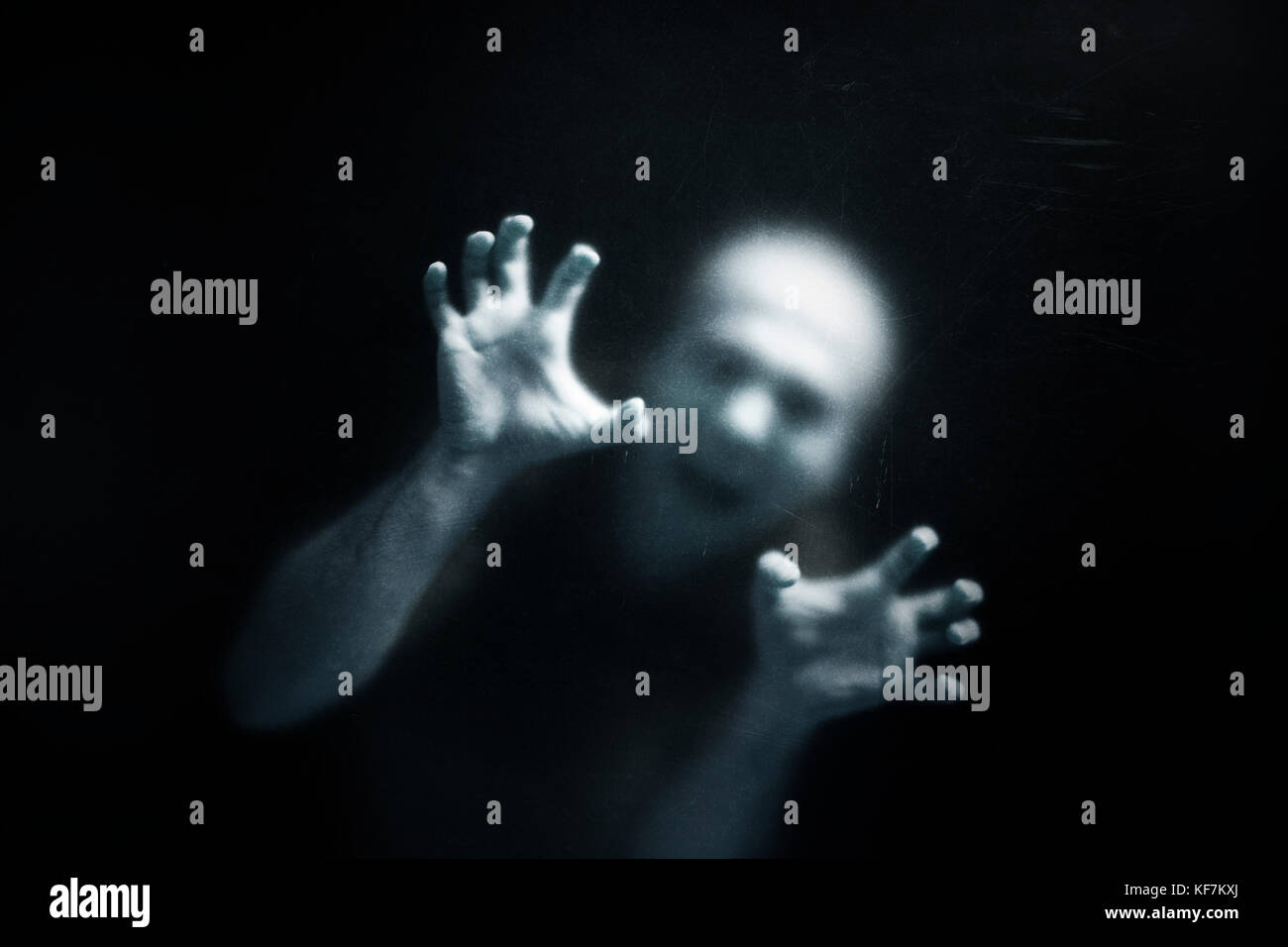 Urlando uomo dietro un polveroso vetro graffiato Foto Stock