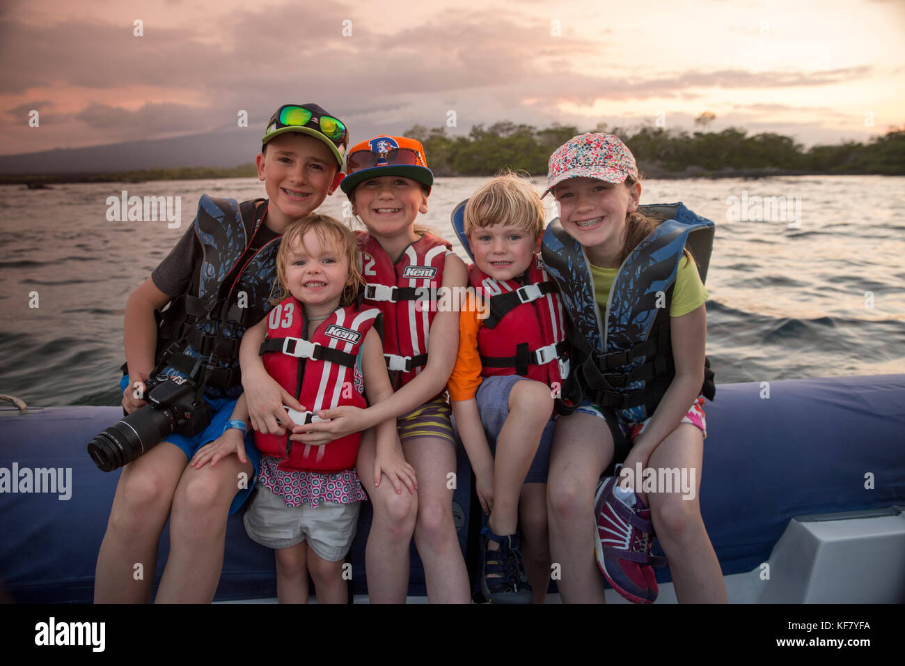 Isole Galapagos, ecuador, bambini viaggiare in zodiac come essi lasciare Fernandina Island al tramonto Foto Stock