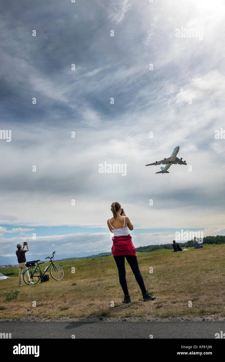Stati Uniti d'America, Alaska, Anchorage, individui sosta per scattare le foto sotto la fine della pista dell'aeroporto mentre in bicicletta sul lungomare Foto Stock