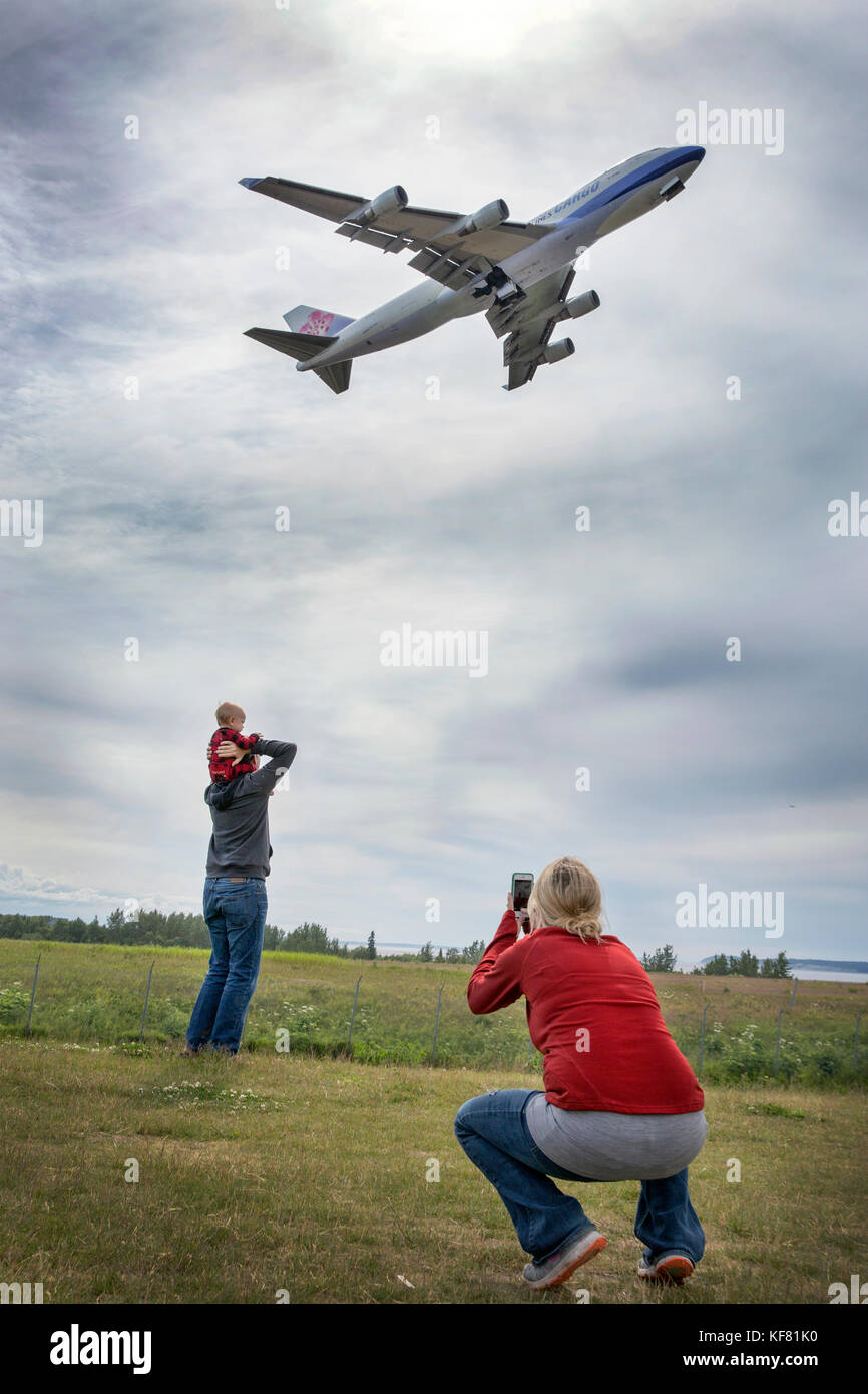Stati Uniti d'America, Alaska, Anchorage, individui sosta per scattare le foto sotto la fine della pista dell'aeroporto mentre in bicicletta sul lungomare Foto Stock