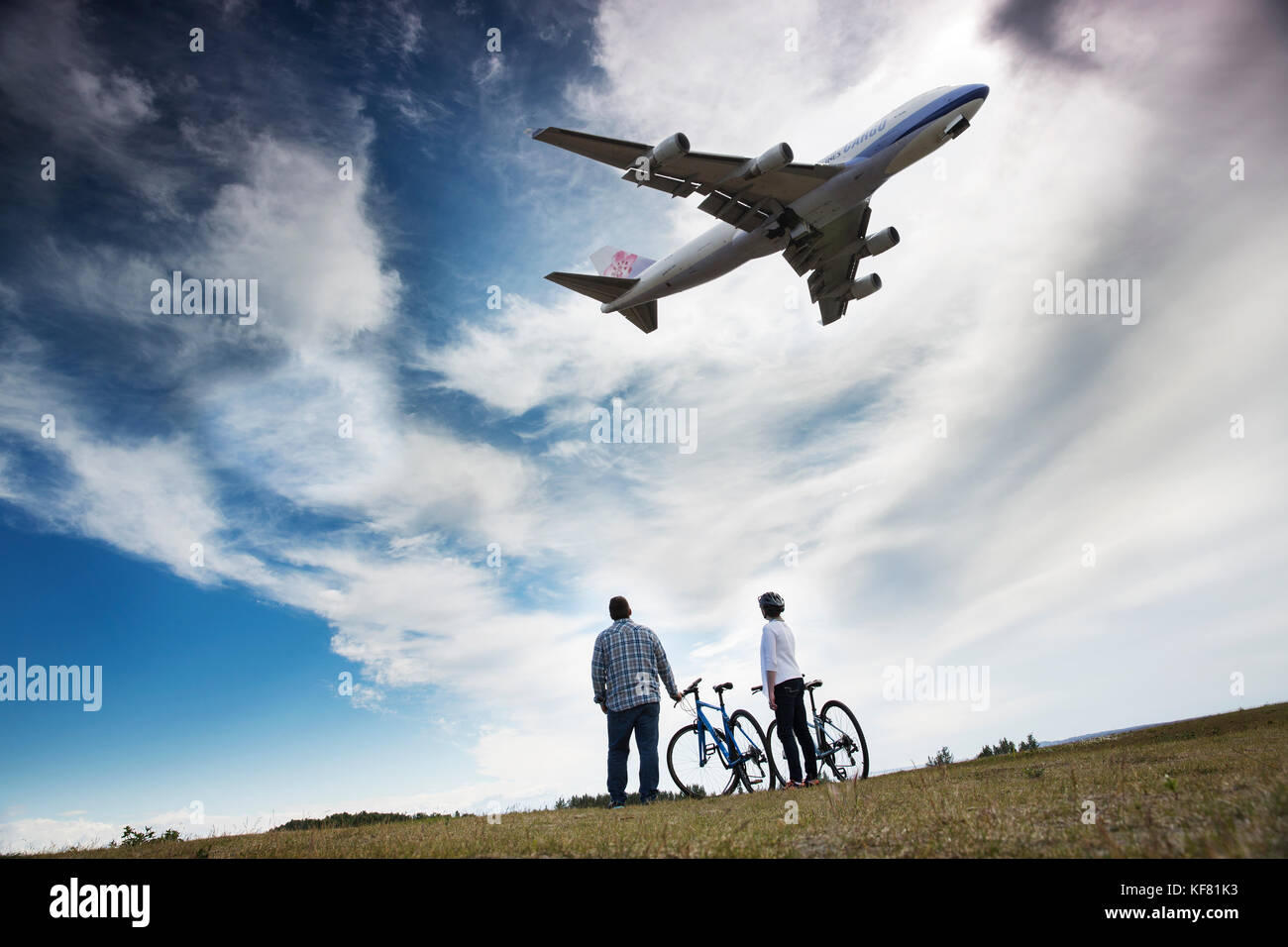 Stati Uniti d'America, Alaska, Anchorage, individui sosta per scattare le foto sotto la fine della pista dell'aeroporto mentre in bicicletta sul lungomare Foto Stock