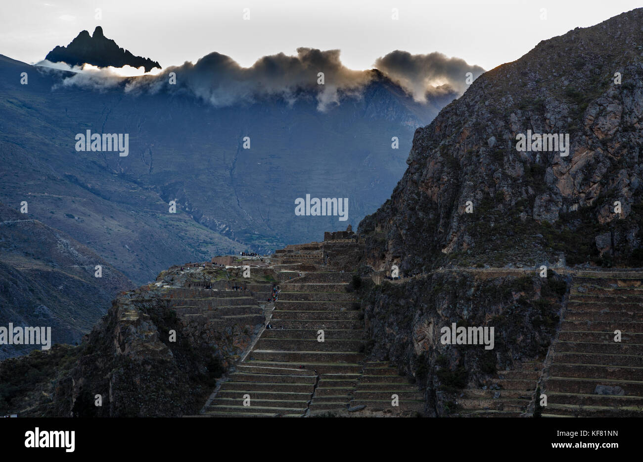 La gente che camminava sulle terrazze del pumatallis, antica fortezza inca e montagne coperte di nuvole, Valle Sacra, Ollantaytambo, Perù Foto Stock