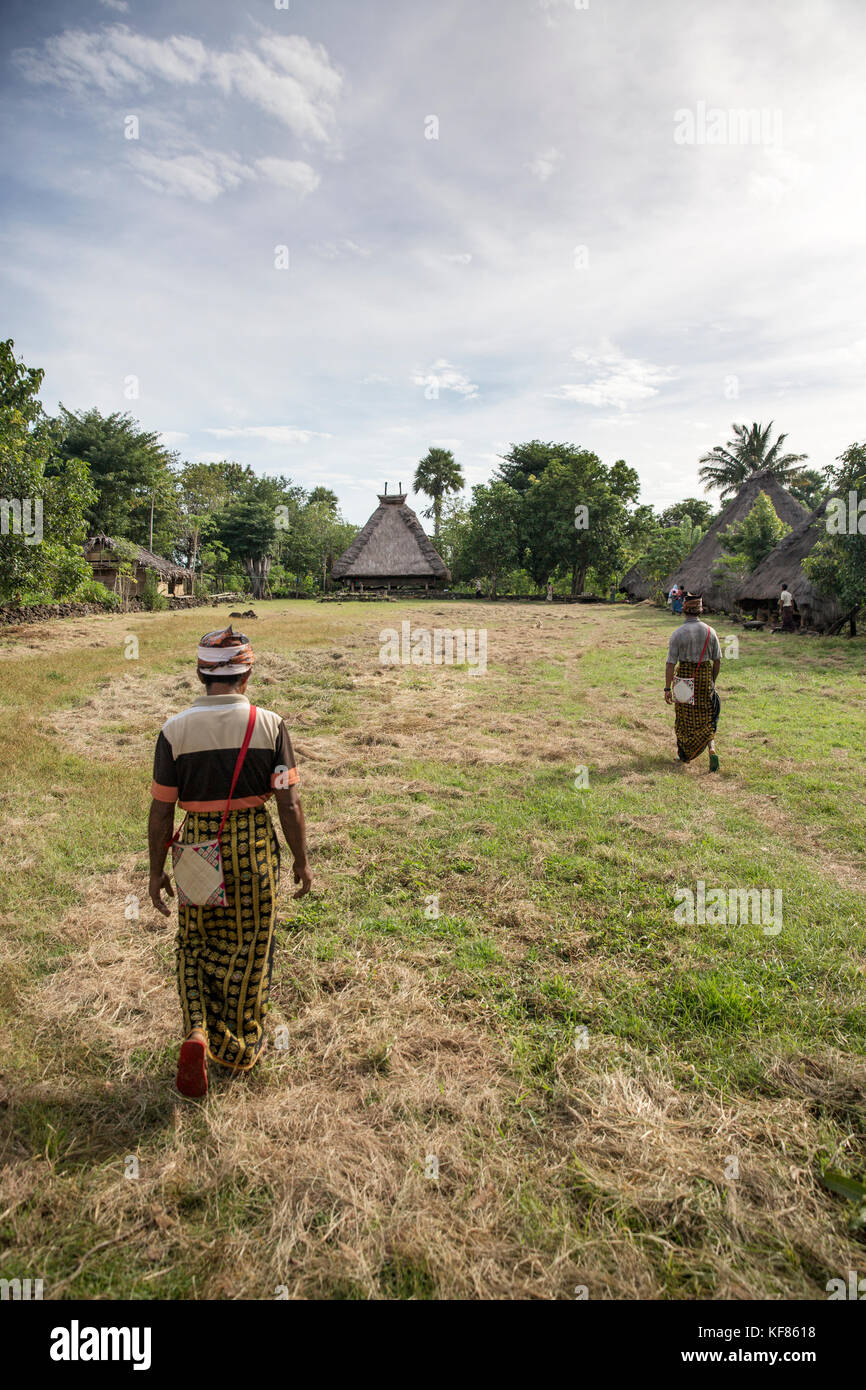 Indonesia, Flores, gli uomini a piedi attraverso il centro di un villaggio chiamato kampung tutubhada in rendu Foto Stock